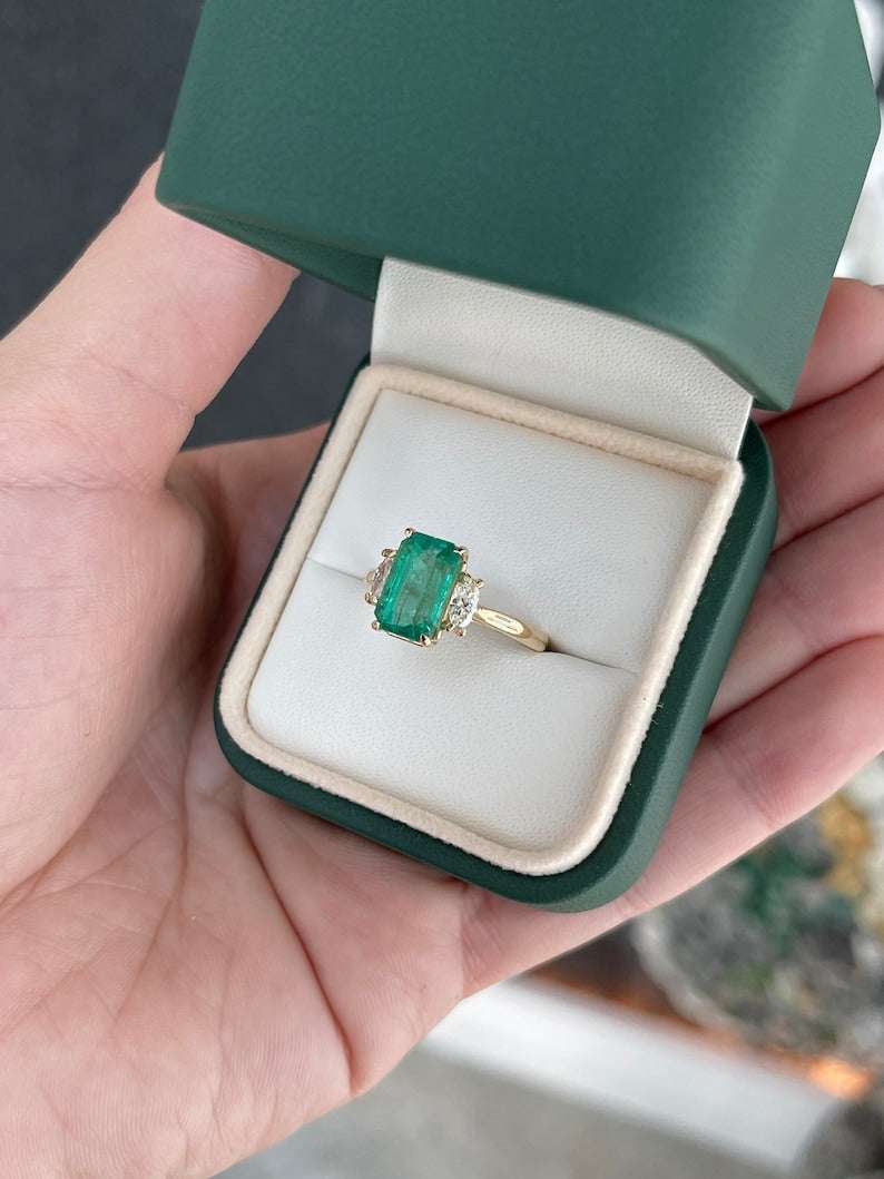 Colombian emerald and diamond three-stone engagement ring with medium bluish green emerald and marquise cut diamonds in 14K gold