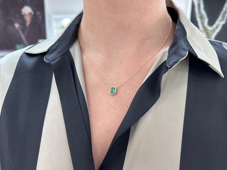 14K gold emerald cut necklace featuring lush green Colombian emerald with adjustable chain and bezel setting, medium length.
