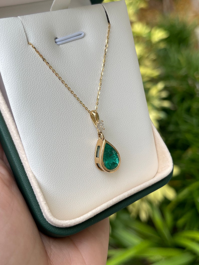 Colombian Emerald teardrop pendant necklace with bezel-set pear-cut emerald and marquise diamond bail accent in 14K gold.