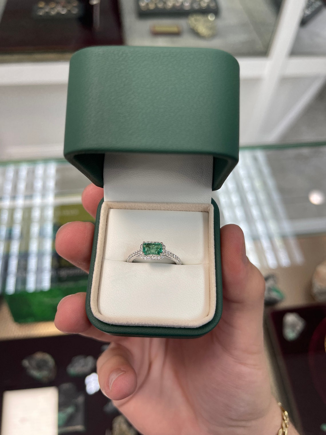14K gold engagement ring with a 1.25 carat emerald-cut center stone and diamond halo, featuring Colombian Emerald branding.