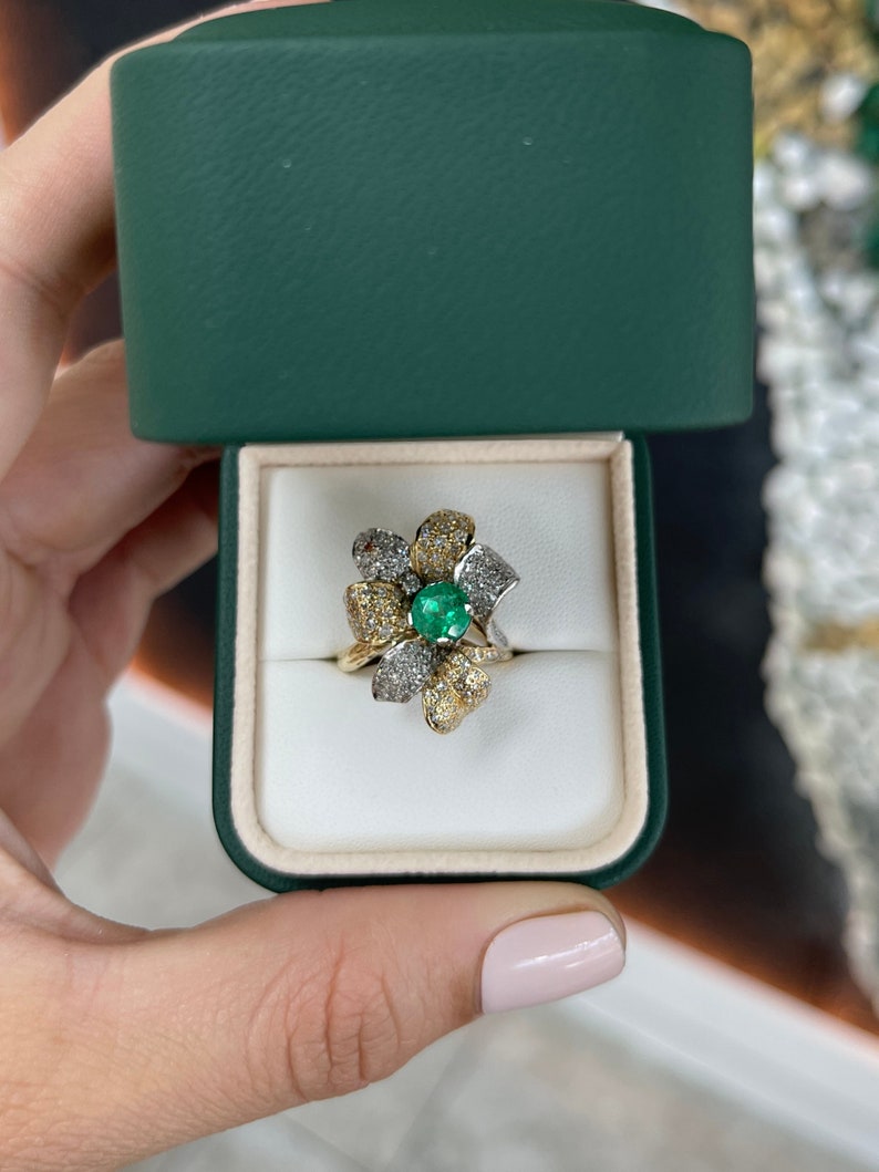 Ladies emerald and diamond cluster floral cocktail ring in 14K gold featuring round cut emeralds and intricate leaf designs.