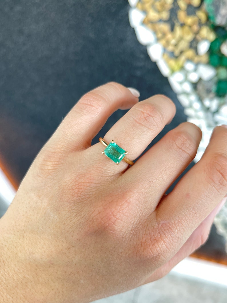 14K gold ladies emerald ring with 2.10 carat east-to-west Colombian emerald solitaire on right hand.