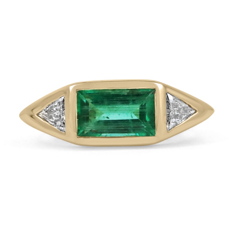 Ladies emerald ring featuring three-stone design with baguette, trillion-cut diamonds, 18K gold, and Colombian emerald accents.