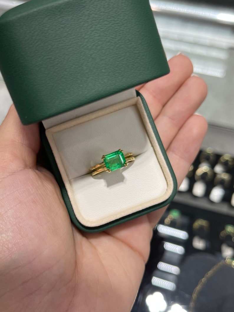 Colombian Emerald ladies ring featuring a 2.68ct emerald cut yellowish-green gemstone, double claw prong, gold split shank.