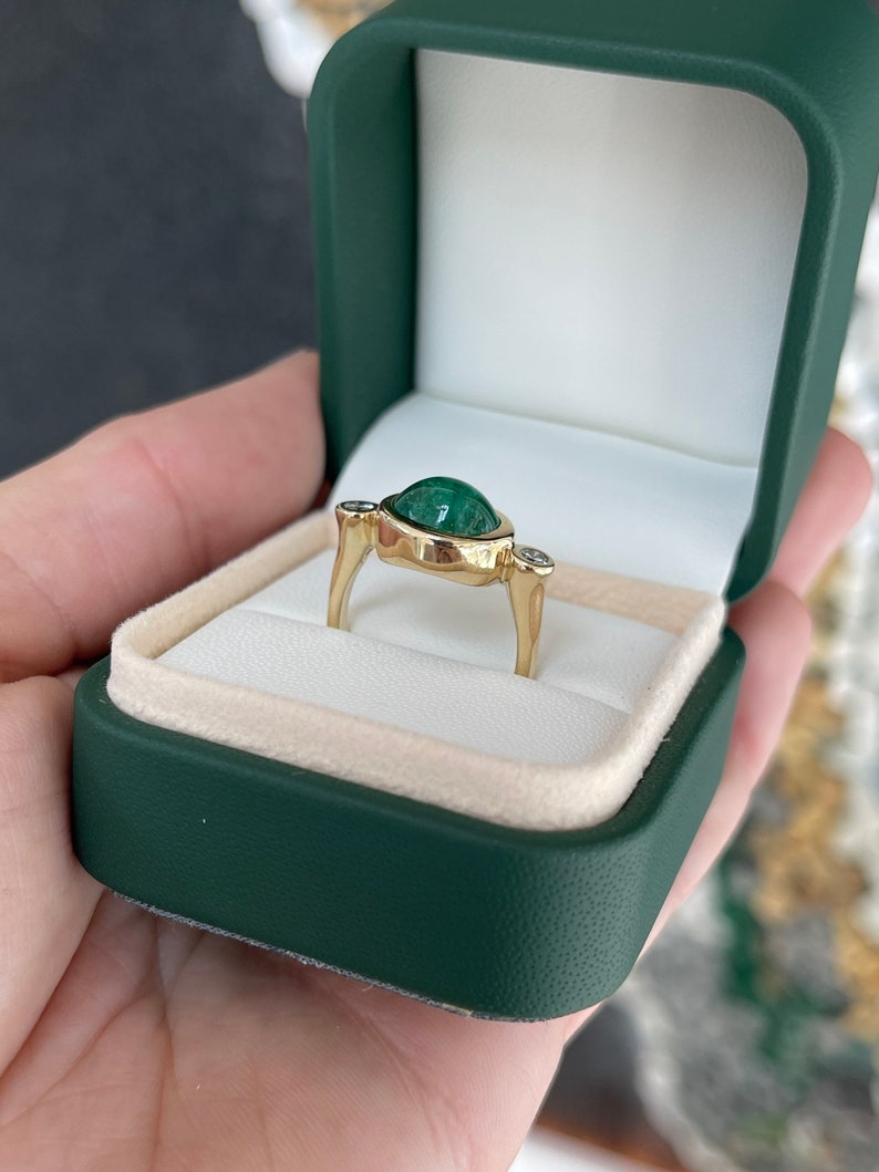 Ladies emerald ring featuring a 4.50tcw oval dark green emerald cabochon with diamond accents in a 14K gold setting.