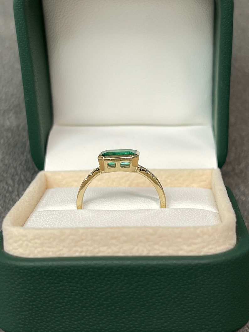 Colombian Emerald 14K ring featuring a 1.15tcw natural emerald cut emerald with diamond accents in a bezel setting