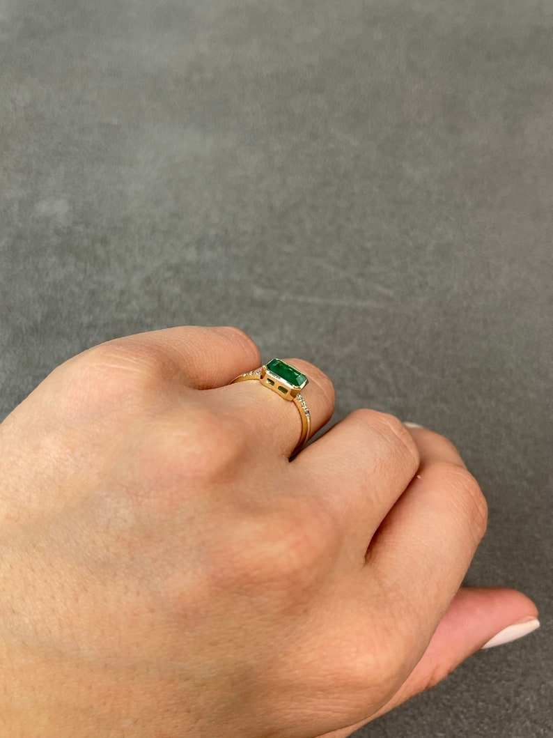 Colombian Emerald 14K ring featuring a 1.15tcw natural emerald cut emerald with diamond accents in a bezel setting