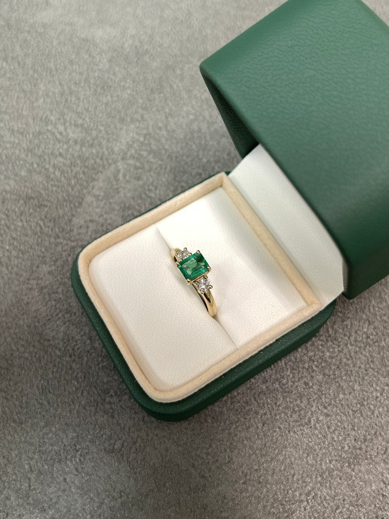 Colombian Emerald 14K gold three-stone ring with round diamonds, featuring a vibrant green emerald centerpiece and sparkling accents.