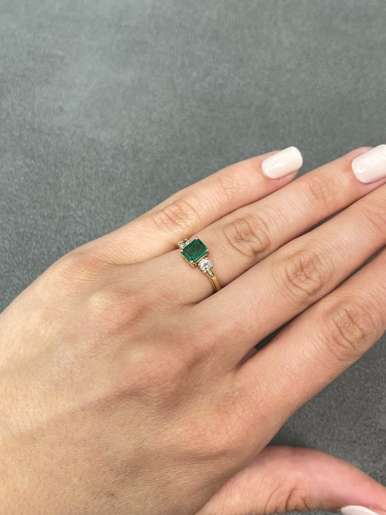 Colombian Emerald 14K gold three-stone ring with brilliant round diamonds and transparent emerald accents.