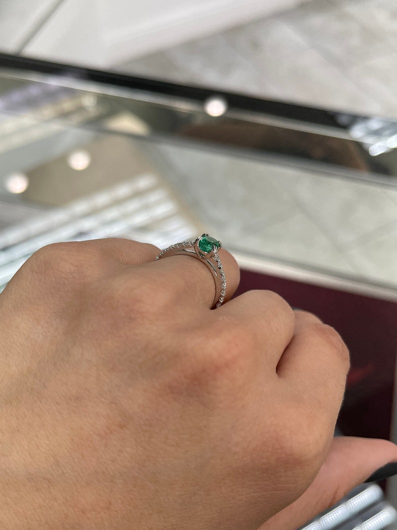 Oval cut natural emerald and diamond engagement ring in 14K white gold, featuring Colombian Emerald brand, detailed close-up.