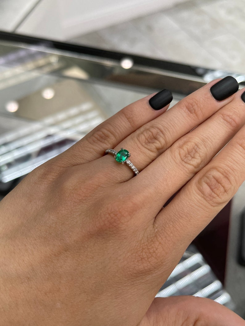 Natural emerald and diamond oval engagement ring in 14K white gold, featuring Colombian Emerald brand, with sparkling gemstones.