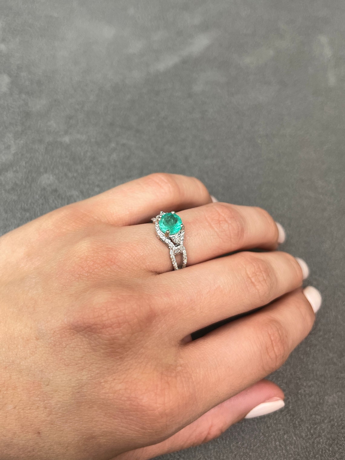Round Colombian emerald engagement ring with diamond halo, 14K gold setting, featuring 1.57 carats total weight.