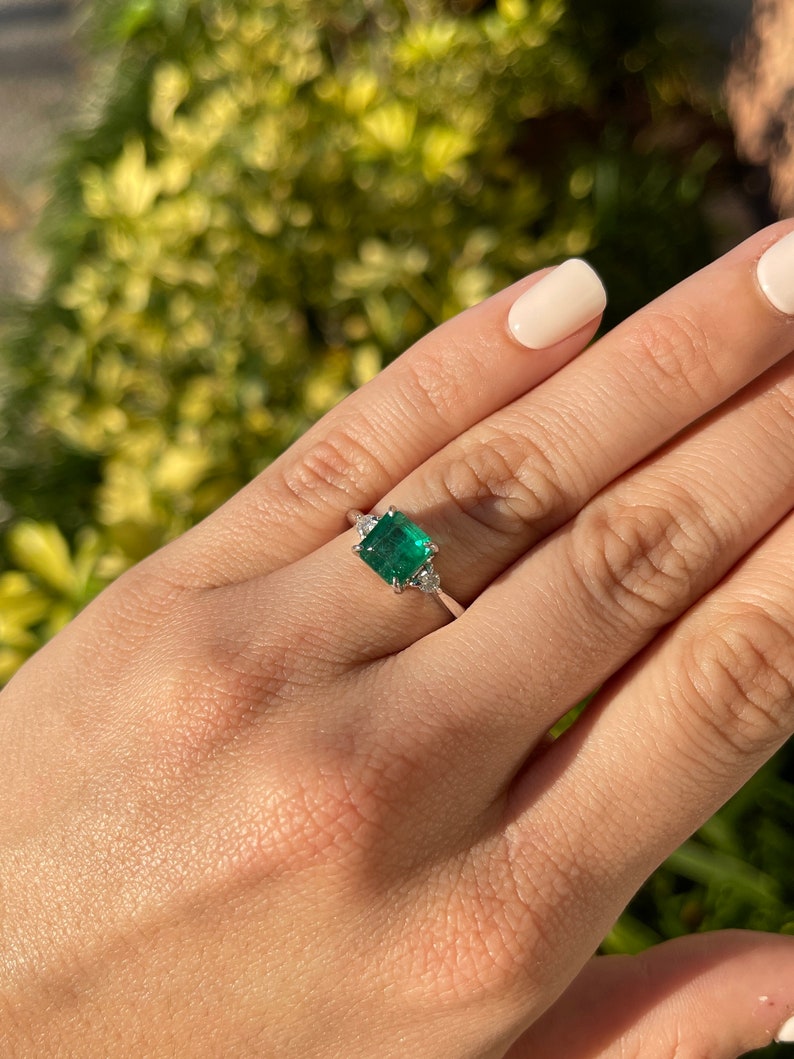 Dark green genuine emerald Asscher cut and diamond 3-stone engagement ring in 14K gold with Colombian Emerald branding.