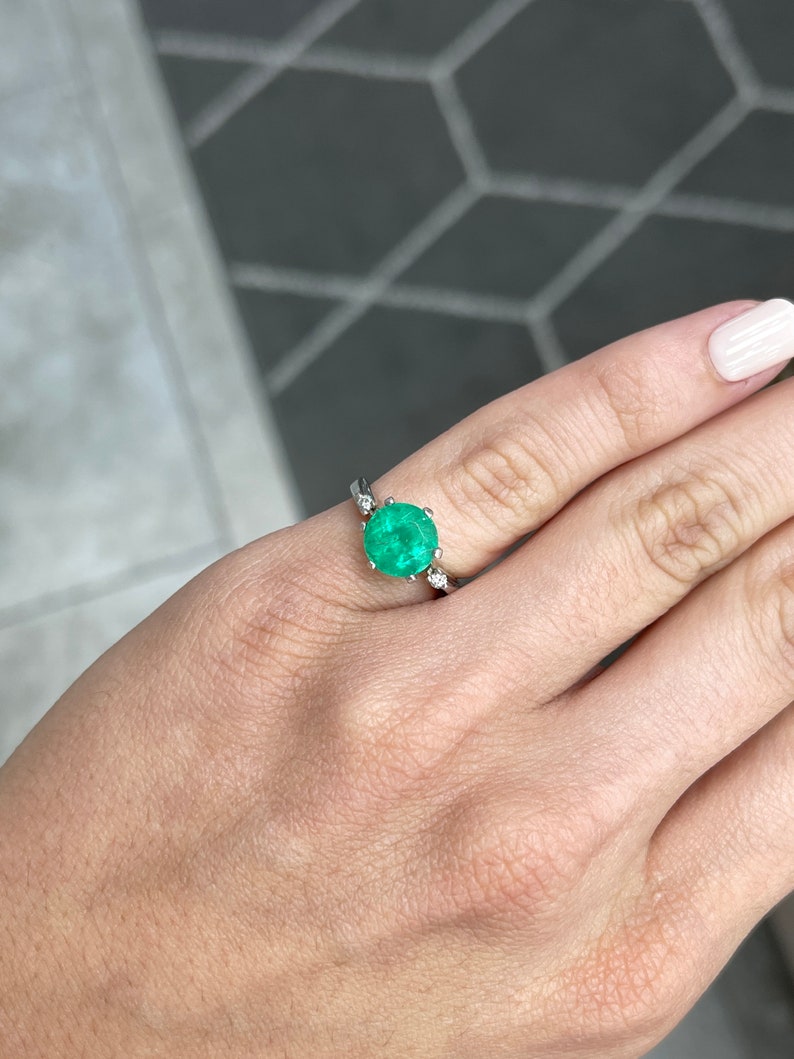 14K Colombian Emerald three-stone gold ring with round cut emeralds and diamond accents, showcasing elegant jewelry design.
