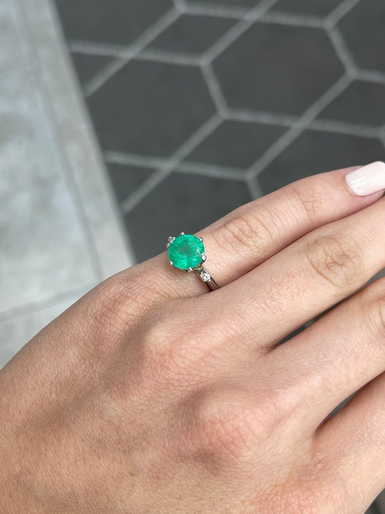 14K gold Colombian emerald three-stone ring with round cut emeralds and diamond accents, showcasing elegant jewelry design.