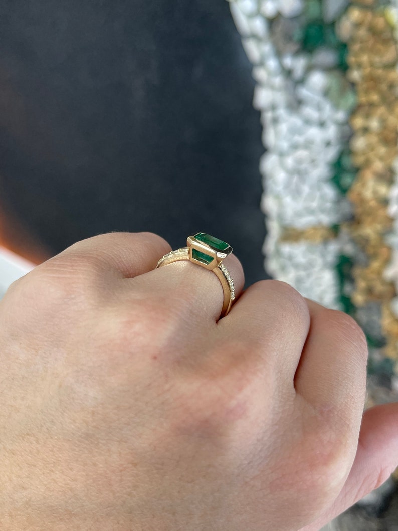 14K gold emerald bezel set ring featuring a 3.22tcw square Colombian emerald with Asscher cut and diamond accents, right hand solitaire.