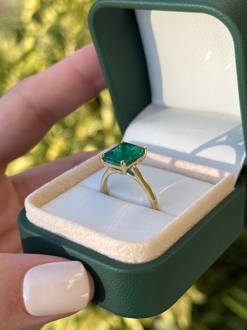 18K gold emerald cut solitaire engagement ring with a 3.84 carat Colombian emerald gemstone, featuring a classic and elegant design.