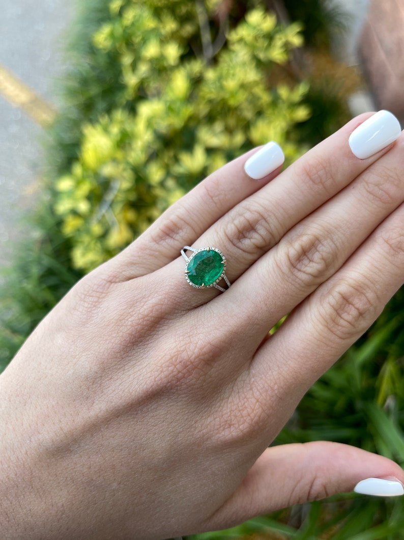 14K Colombian Emerald engagement ring with oval emerald centerpiece, diamond halo, and split shank design.