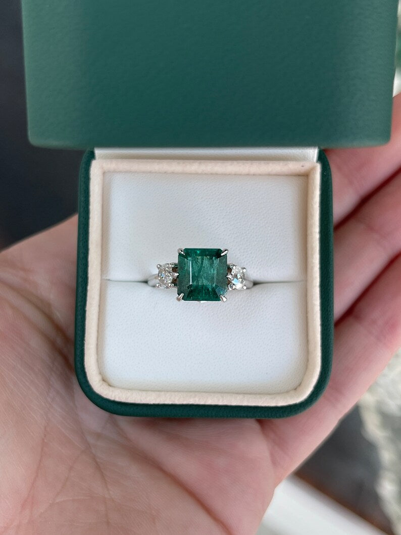 14K gold 3-stone engagement ring featuring intense dark green emerald and round diamonds, crafted by Colombian Emerald.