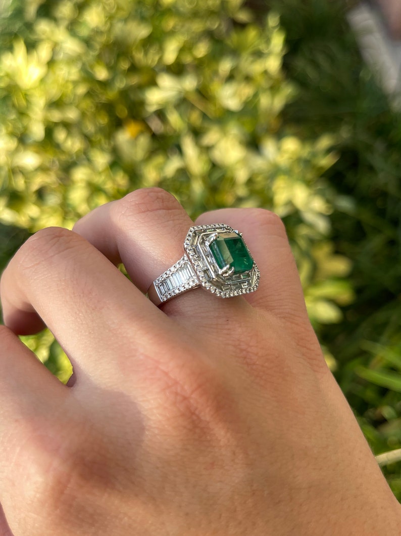 Colombian Emerald 18K white gold anniversary ring with a large emerald center, surrounded by diamonds in a halo setting.