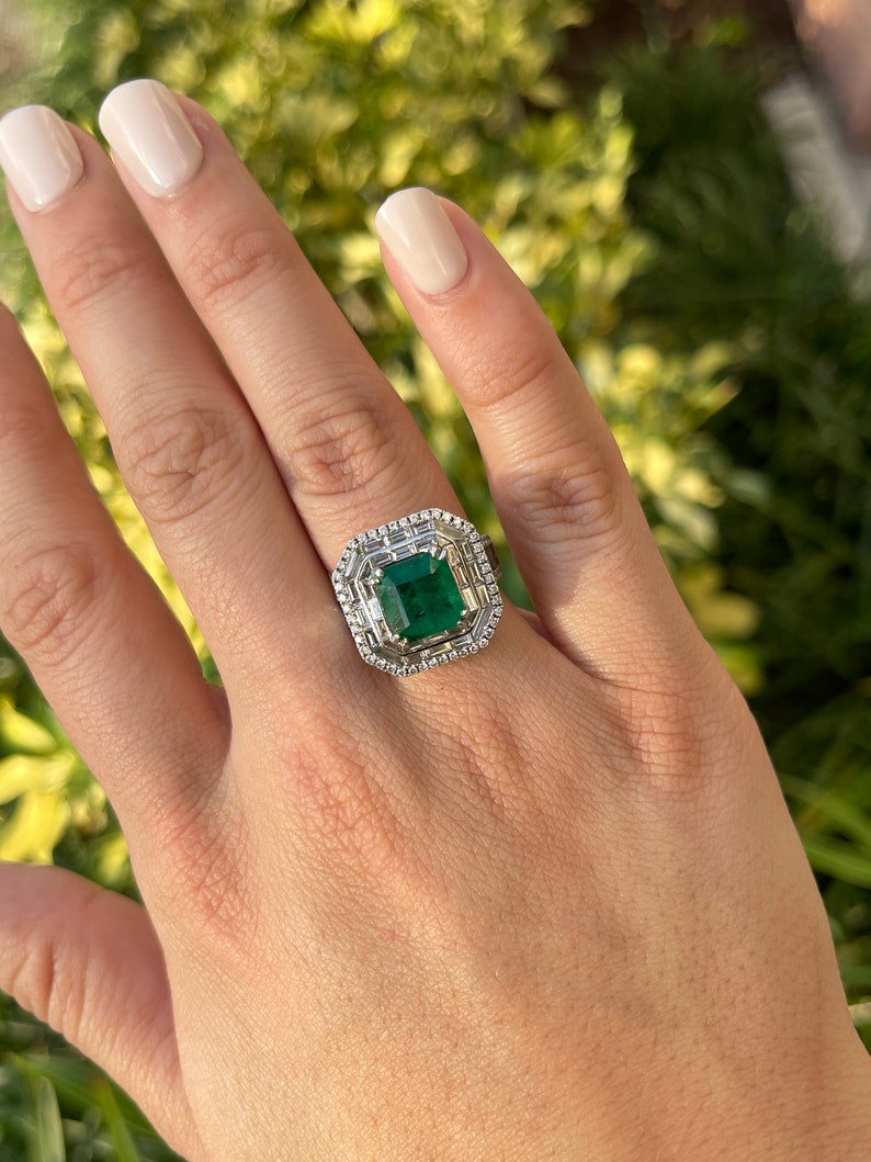Colombian Emerald 7.39tcw 18K white gold triple diamond halo anniversary ring with emerald and diamond accents.