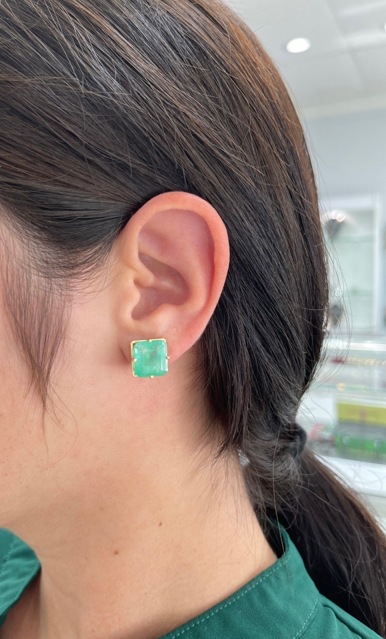 Large 13 carat Colombian emerald asscher cut solitaire earrings on ear for women 14K gold