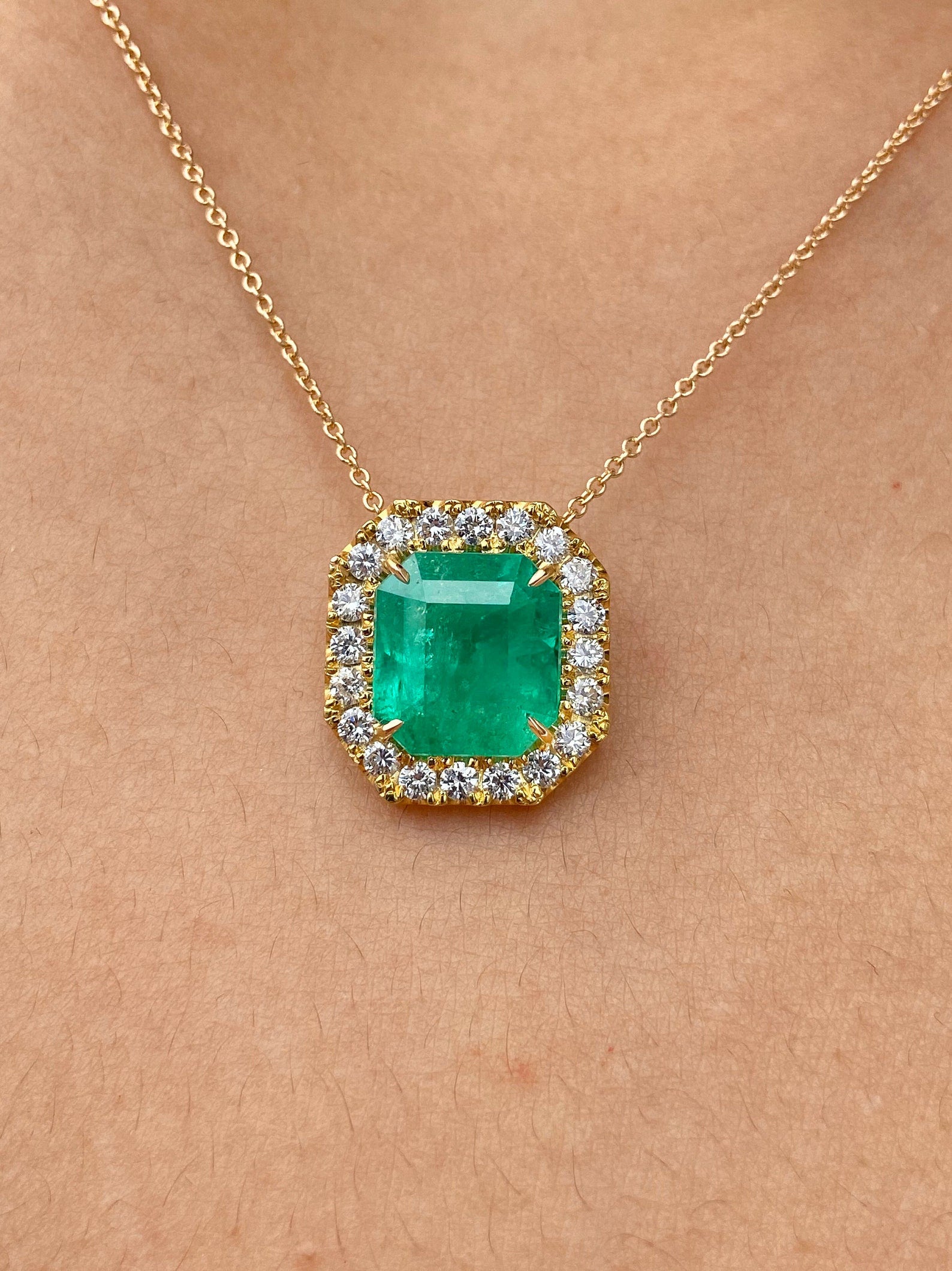 Square cut Colombian emerald and diamond halo pendant necklace in 14k yellow gold with 4.60tcw gemstones.
