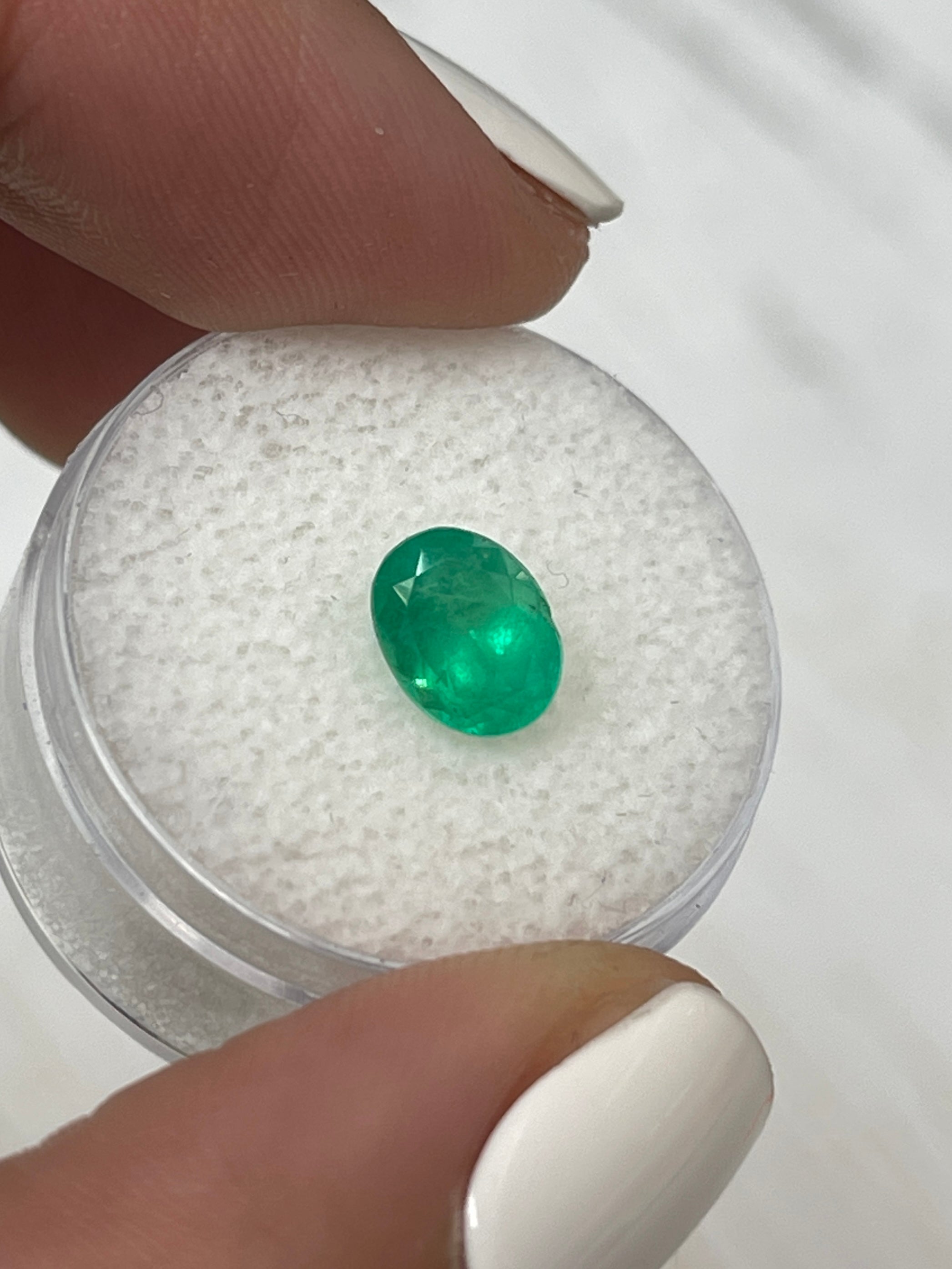 Bright apple green 1.40 carat natural Colombian emerald in oval cut, showcasing vibrant color and clarity.