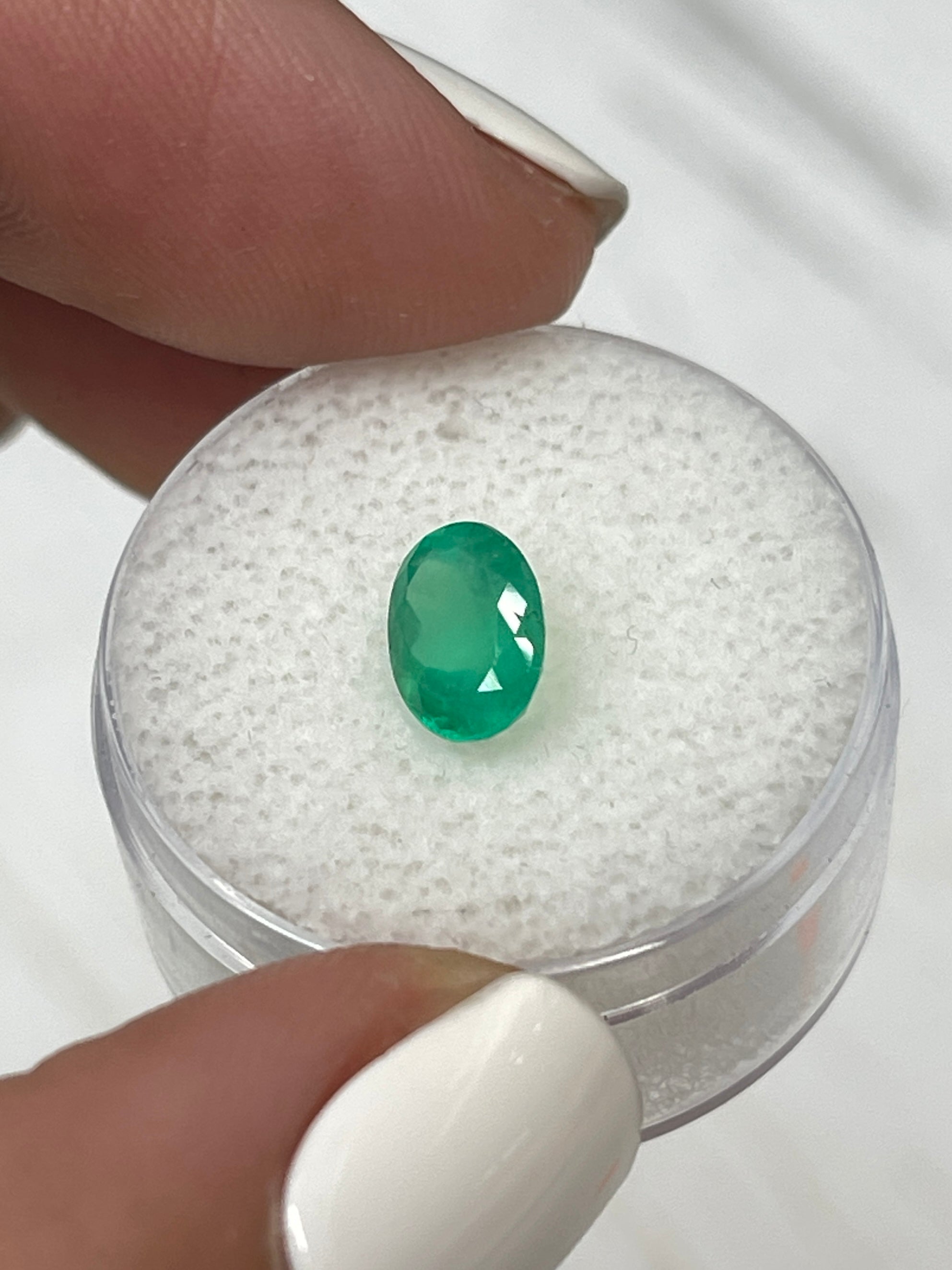 Bright 1.40 carat oval cut Colombian emerald from JR Colombian Emeralds, showcasing vivid apple green natural gemstone.