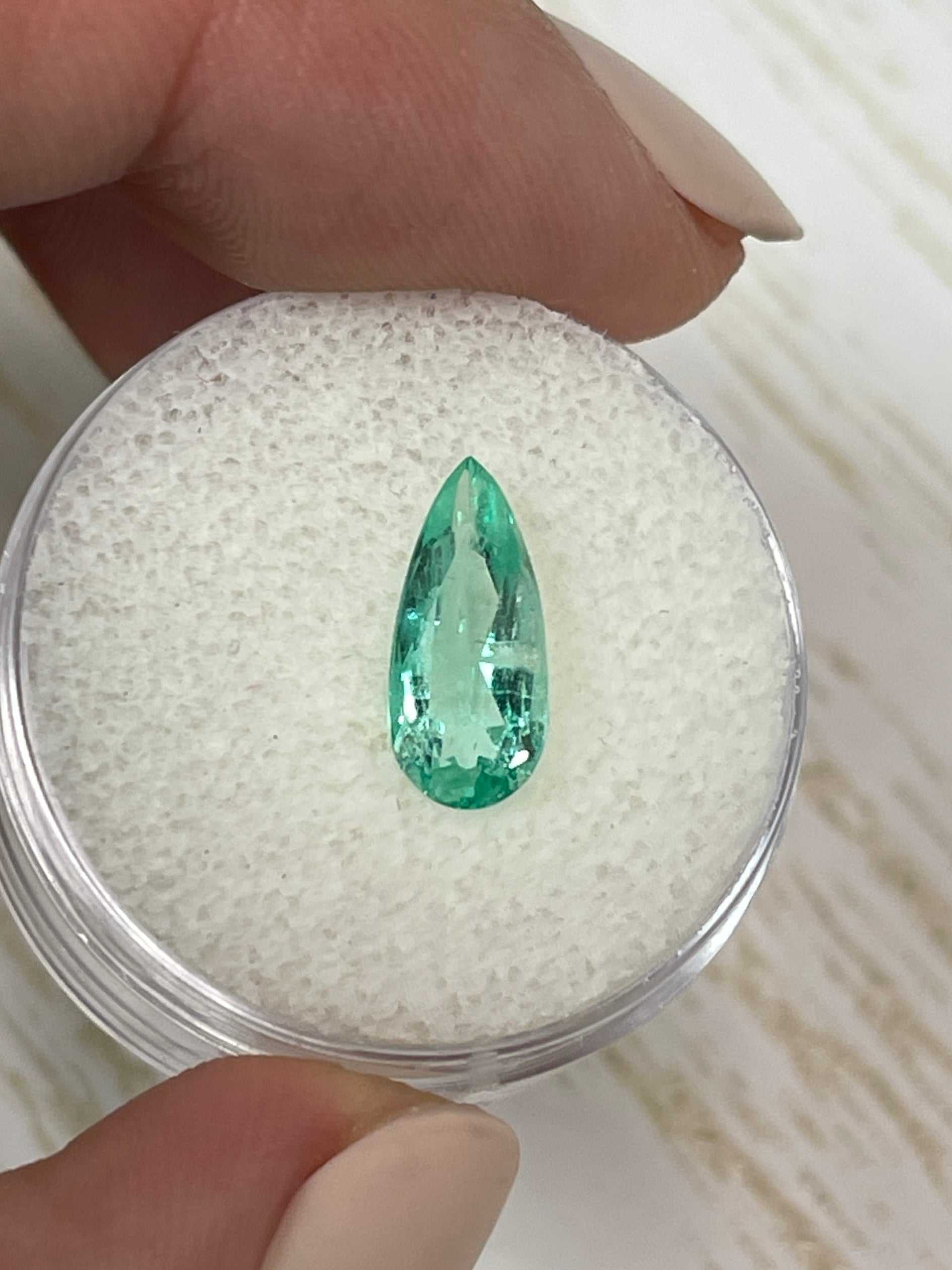 1.49 carat slender green natural Colombian emerald loose gemstone in pear cut, showcasing vibrant color and clarity.