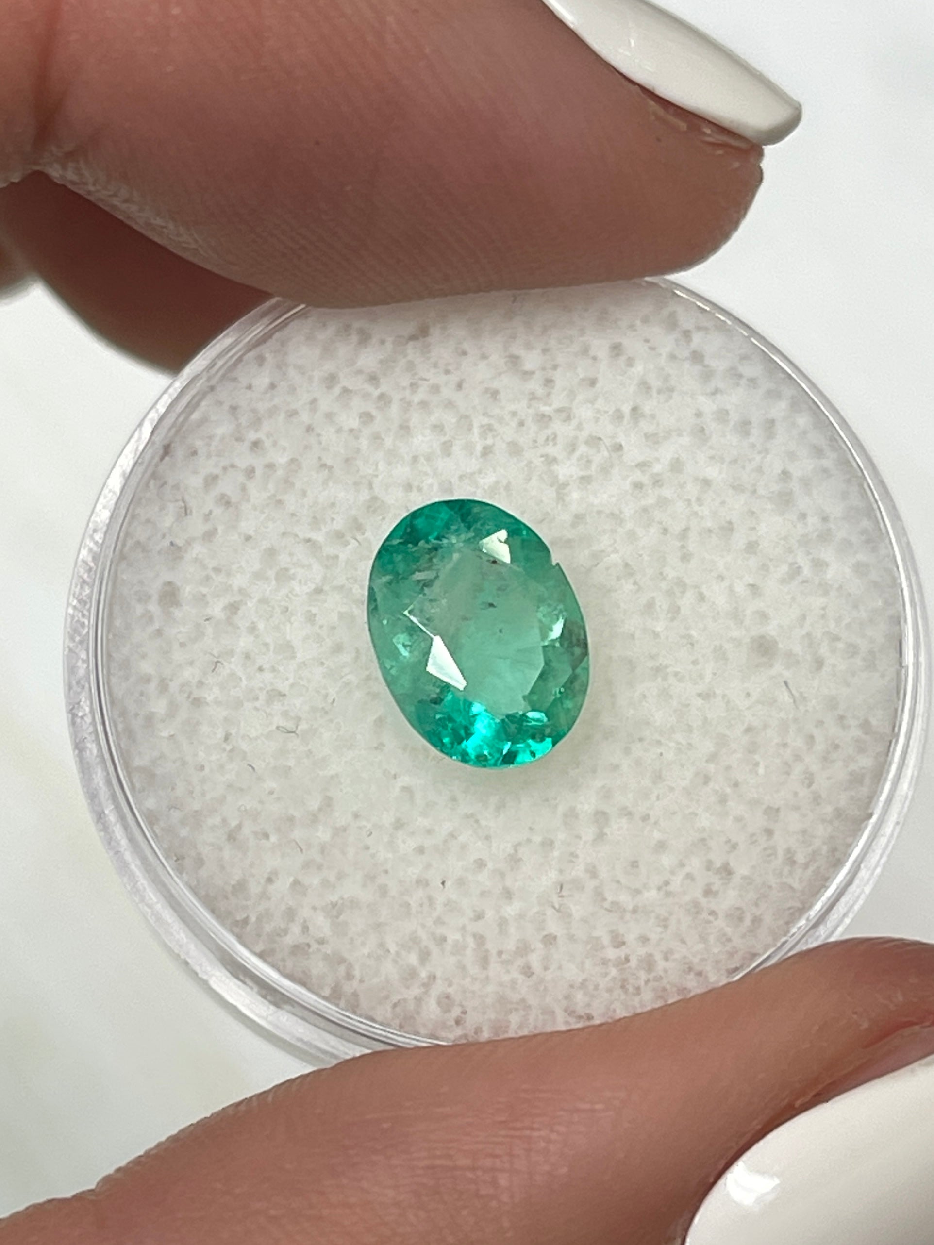 1.77 carat medium light green natural Colombian emerald loose gemstone in oval cut, showcasing vibrant color and clarity.
