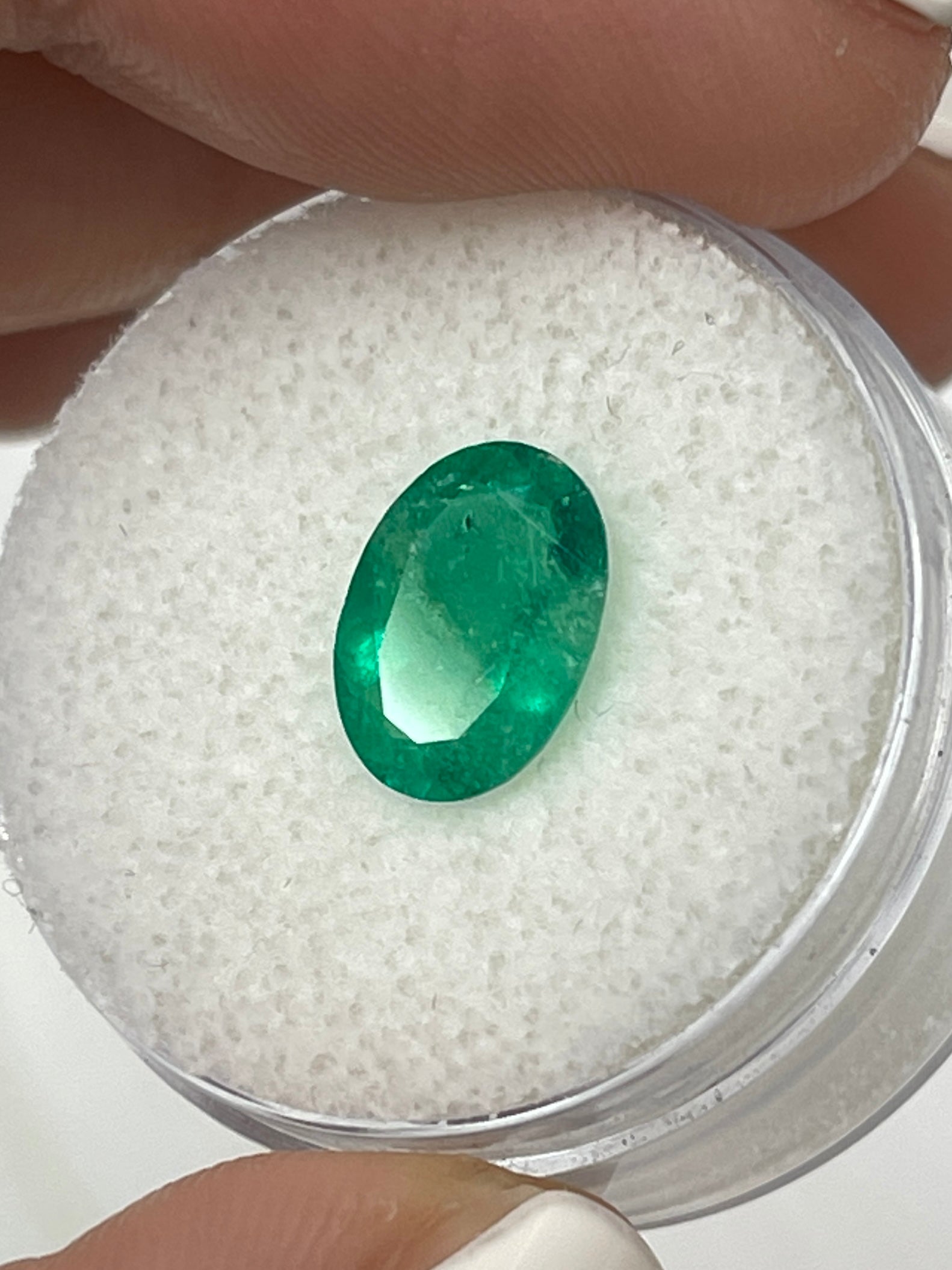 Oval-cut 1.94 carat green natural Colombian emerald gemstone from JR Colombian Emeralds, displayed on a white background.