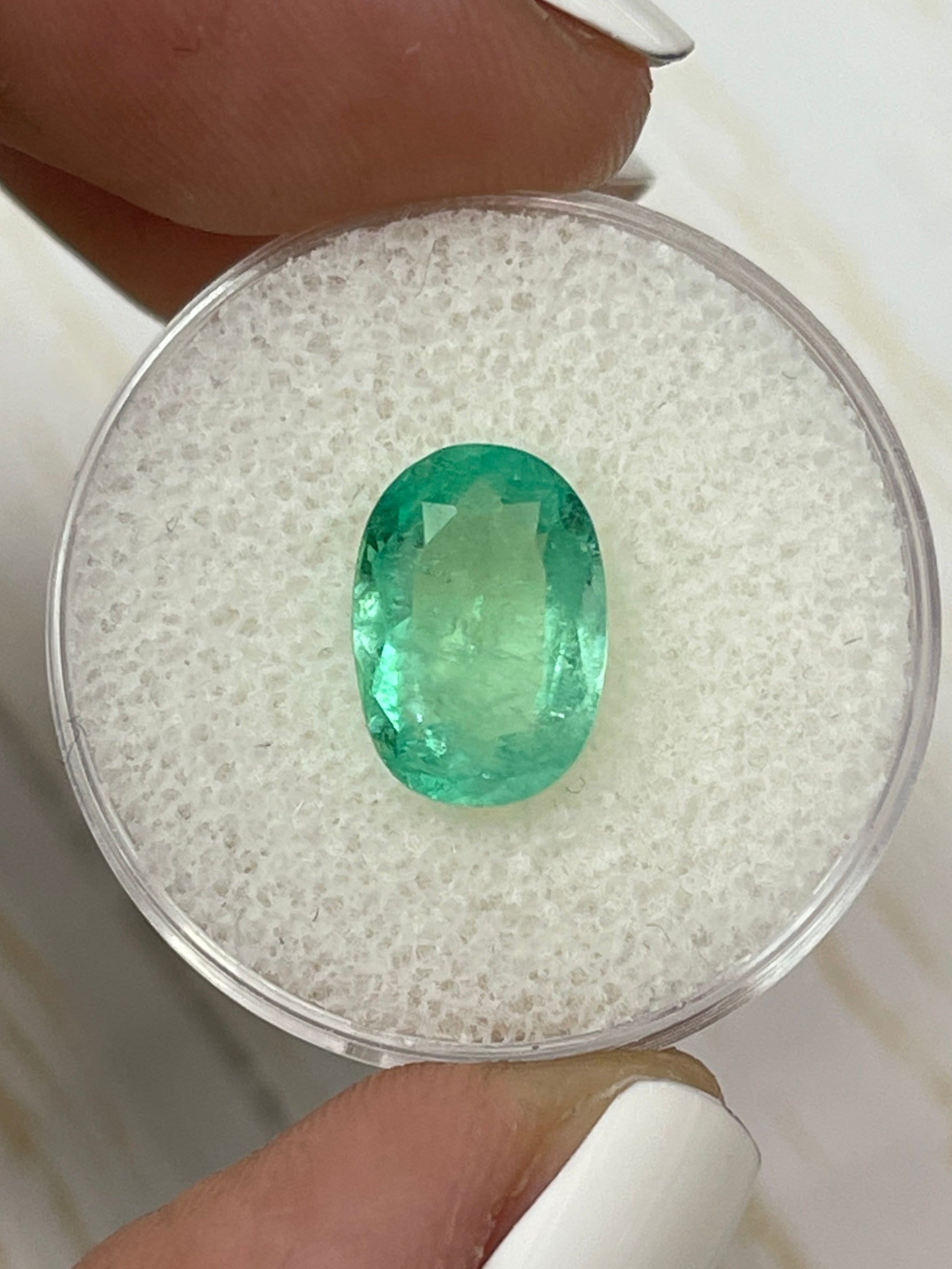 2.78 carat light yellowish-green natural Colombian emerald in oval cut, displayed as a loose gemstone by JR Colombian Emeralds.