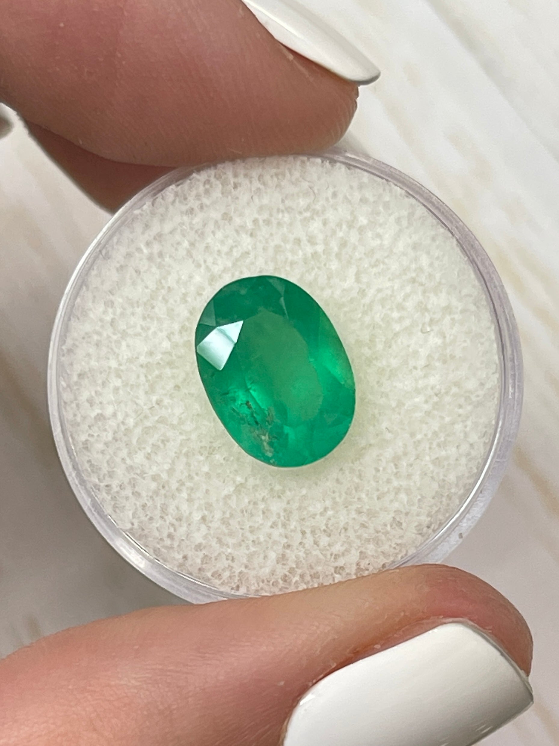 3.46 carat neon green natural Colombian emerald loose oval cut gemstone from JR Colombian Emeralds displayed on a white background.