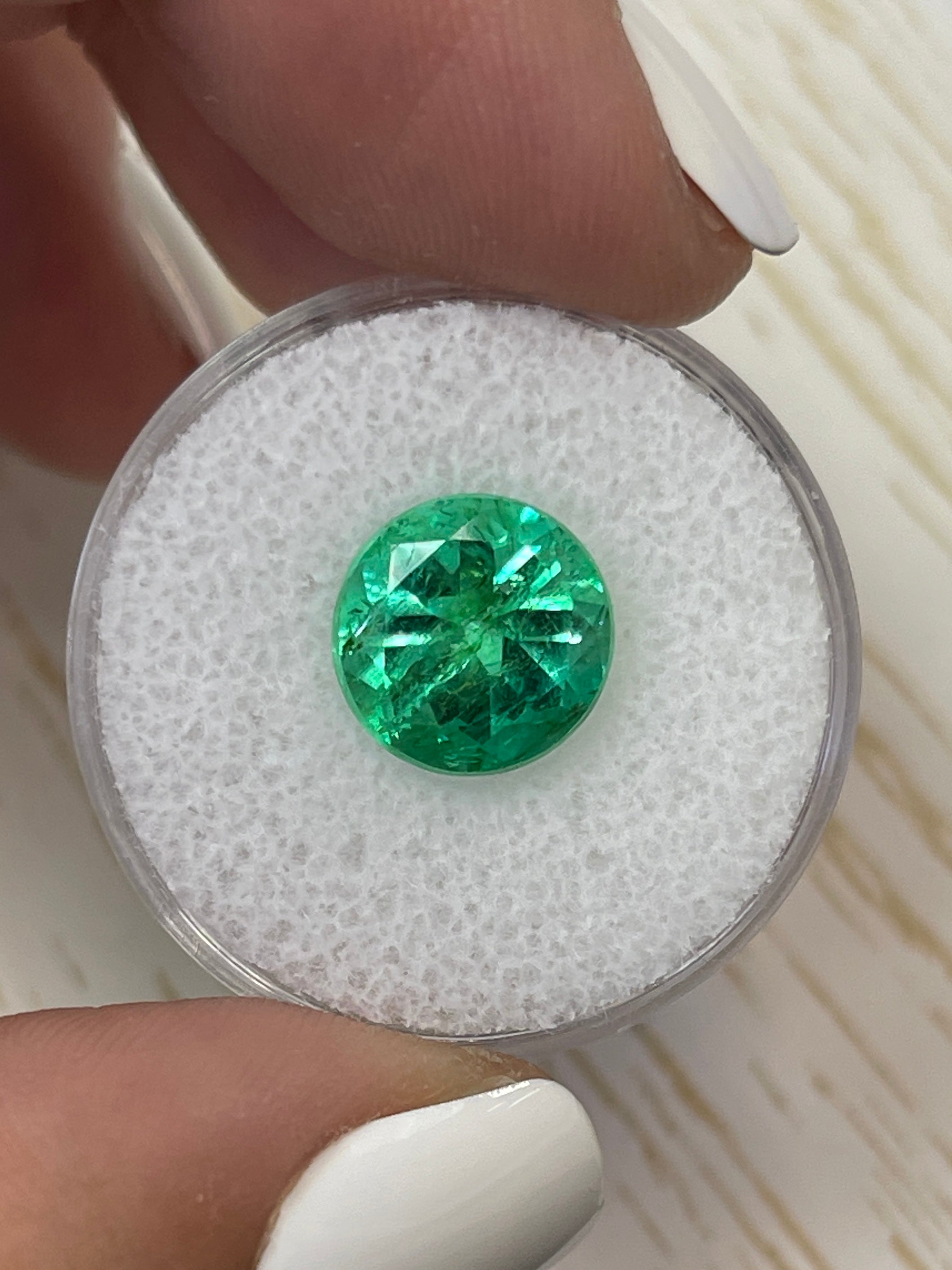 4.14 carat natural round Colombian emerald loose gemstone with vibrant green color, certified and set in a simple display.