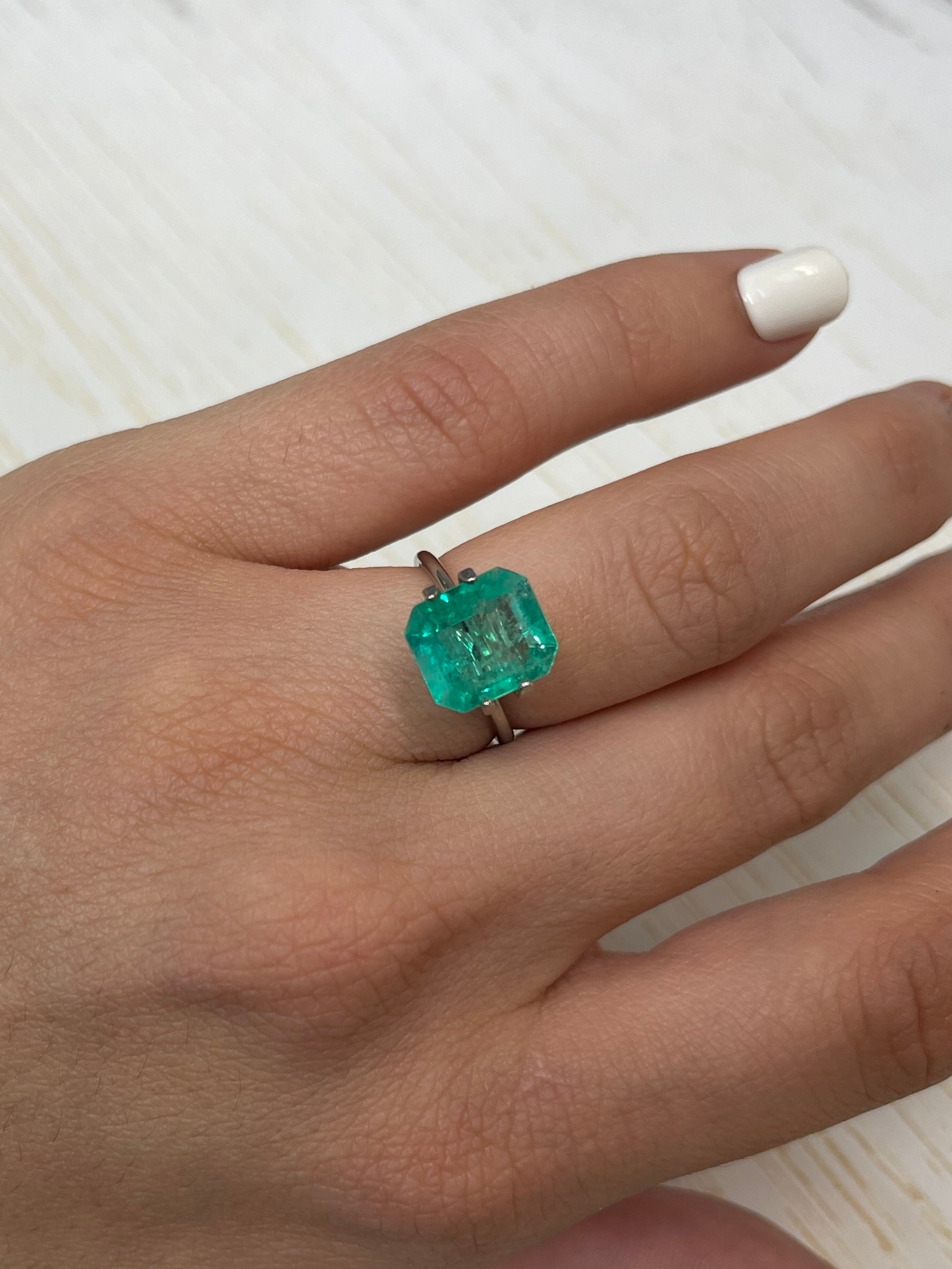 4.17 carat bluish green natural Colombian emerald loose gemstone in classic emerald cut, displayed on a neutral background.