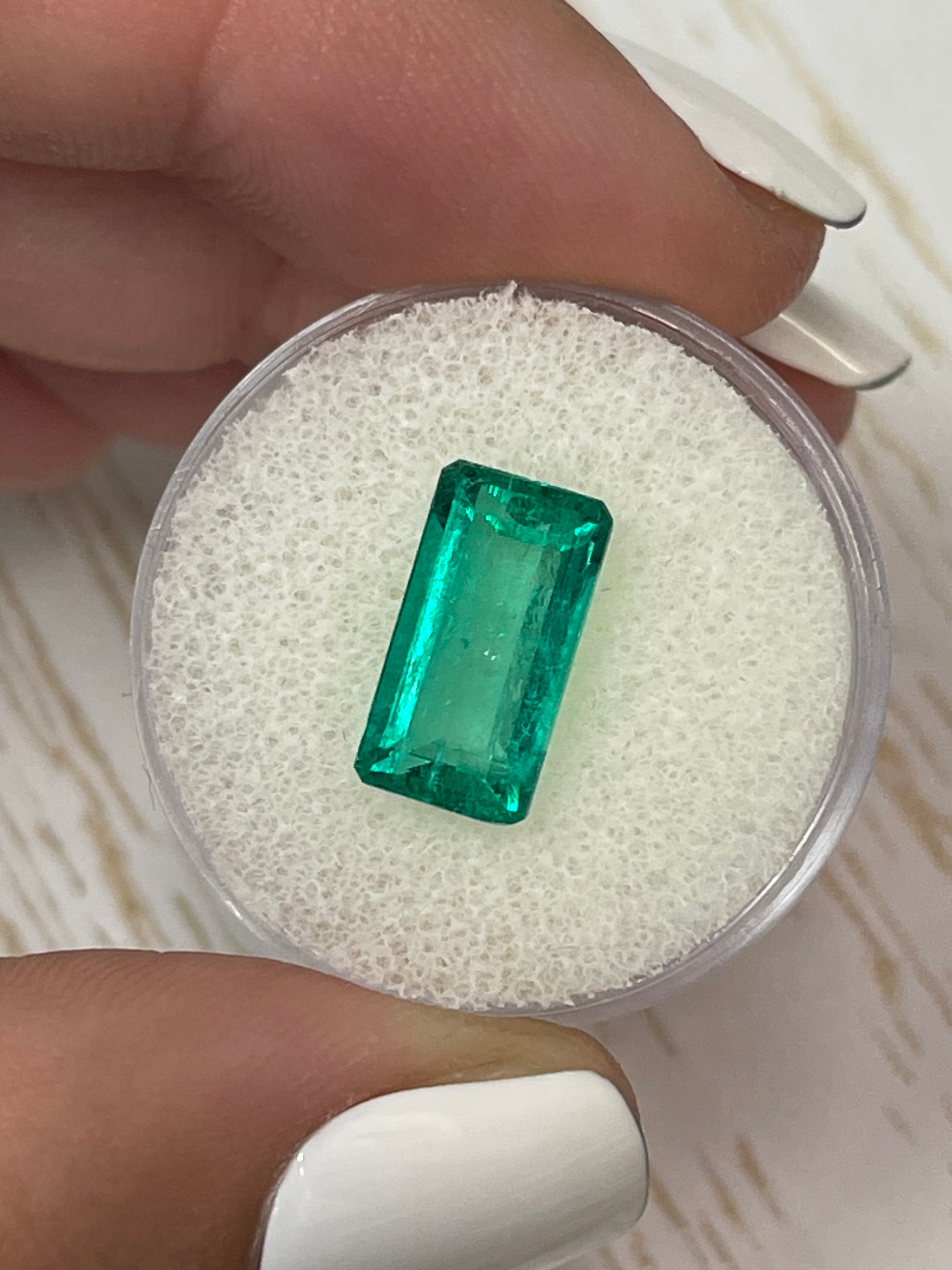 Vivid bluish-green 4.26 carat natural Colombian emerald in elongated emerald cut, displayed as a loose gemstone.