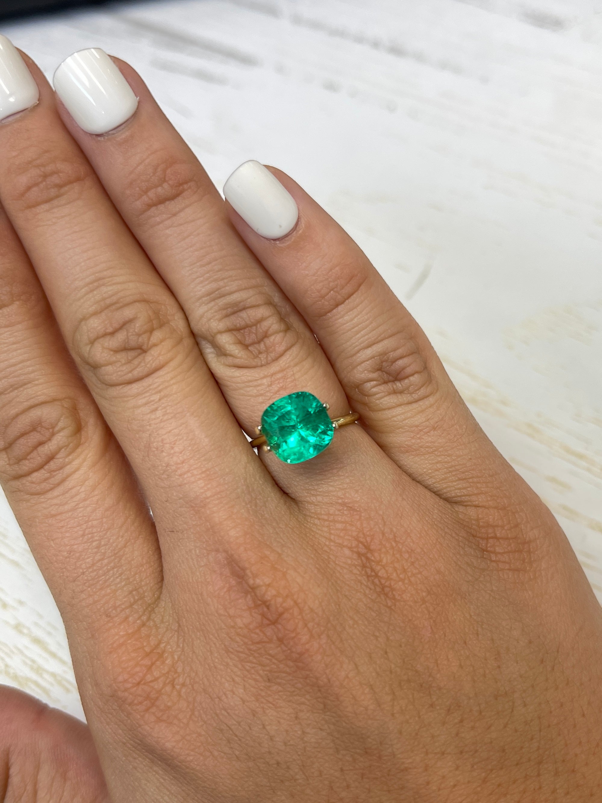 Bright green 4.72 carat Colombian emerald, cushion cut, showcasing natural brilliance and clarity against a neutral background.