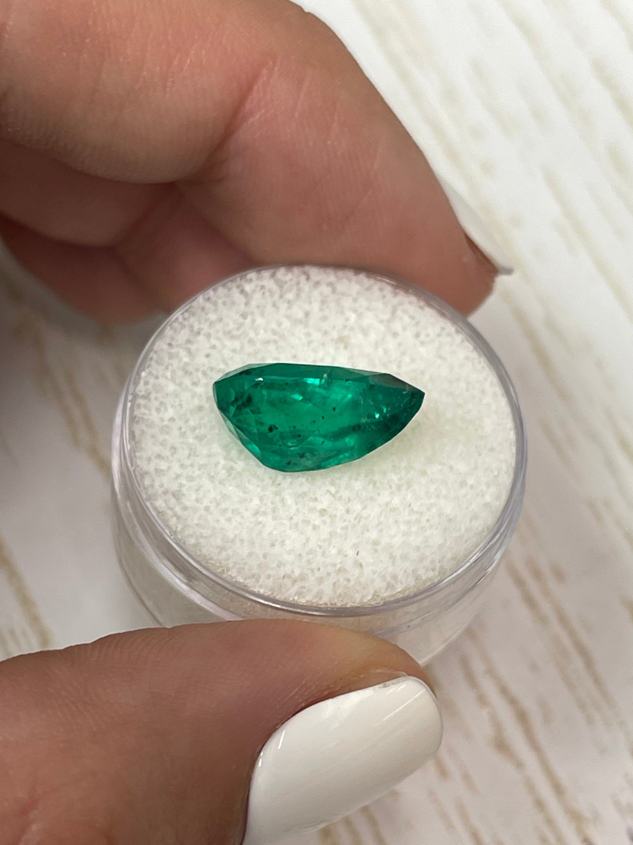 Natural 5.18 carat Colombian emerald loose gemstone with pear cut and freckles, shown in close-up image.