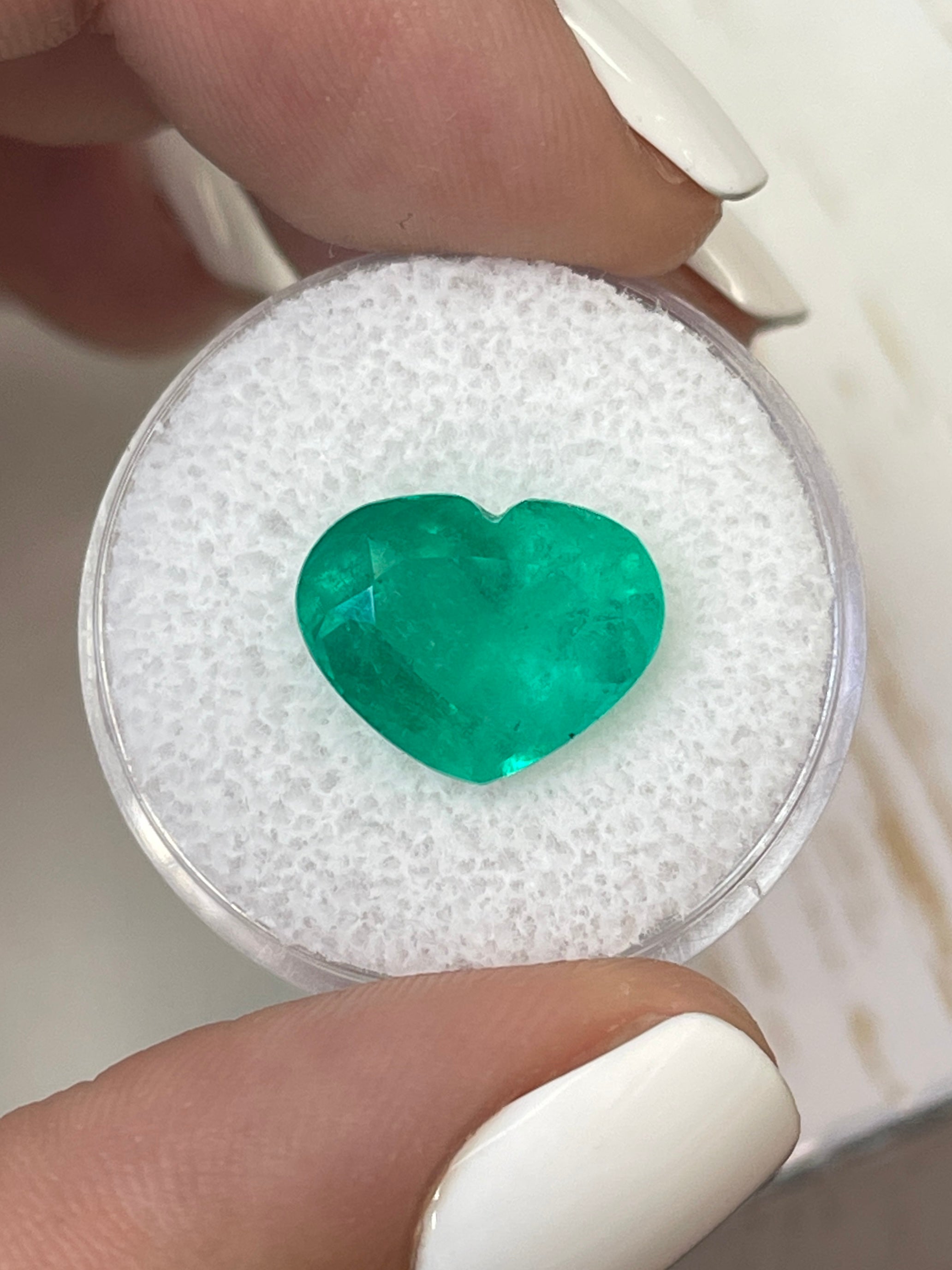 Bright green 5.80 carat natural Colombian emerald loose gemstone in heart cut, showcasing vibrant color and clarity.