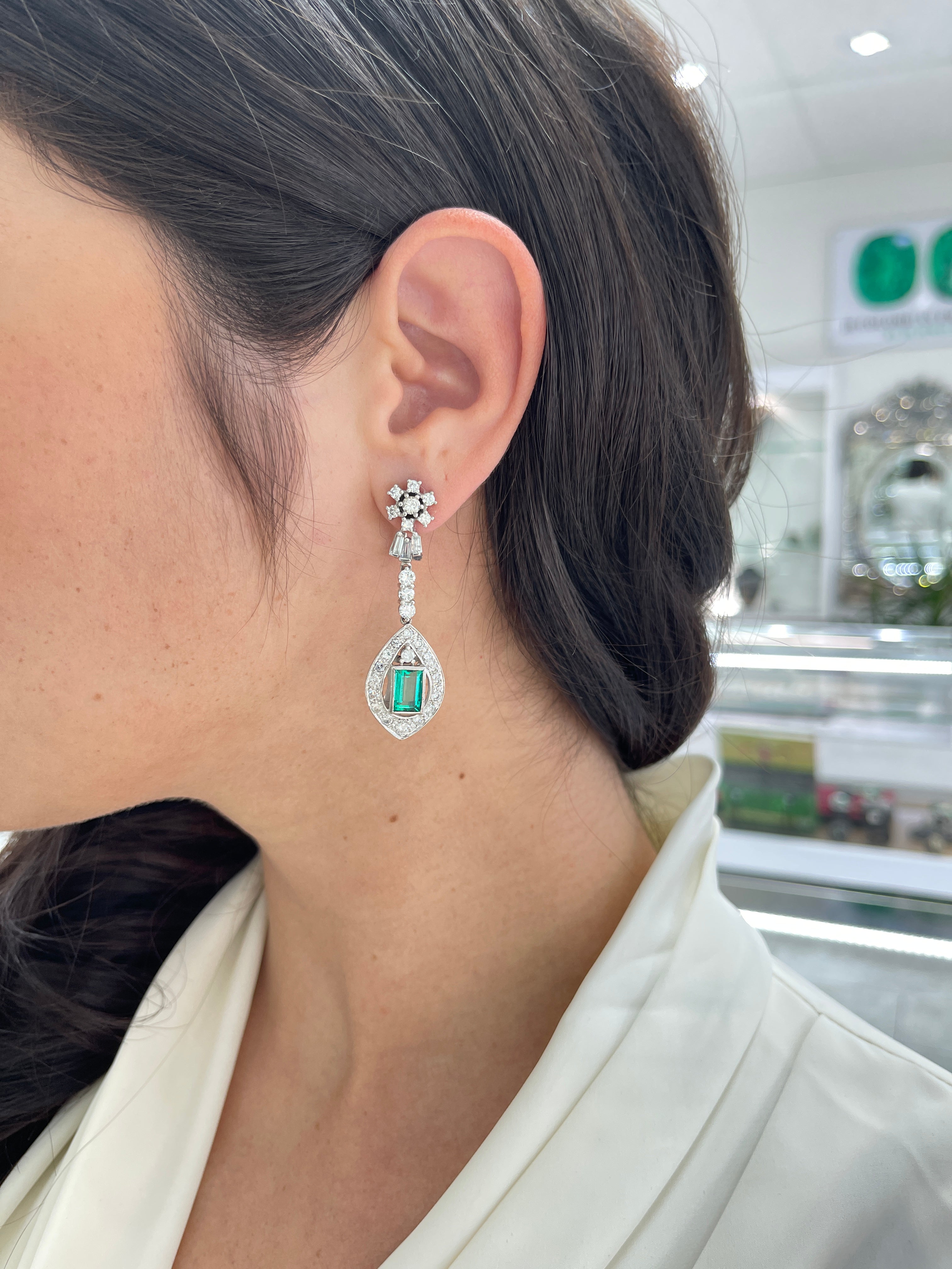 Art Deco Colombian emerald and diamond dangle earrings in 18K gold, featuring 6.20tcw of vibrant green emeralds and sparkling diamonds.