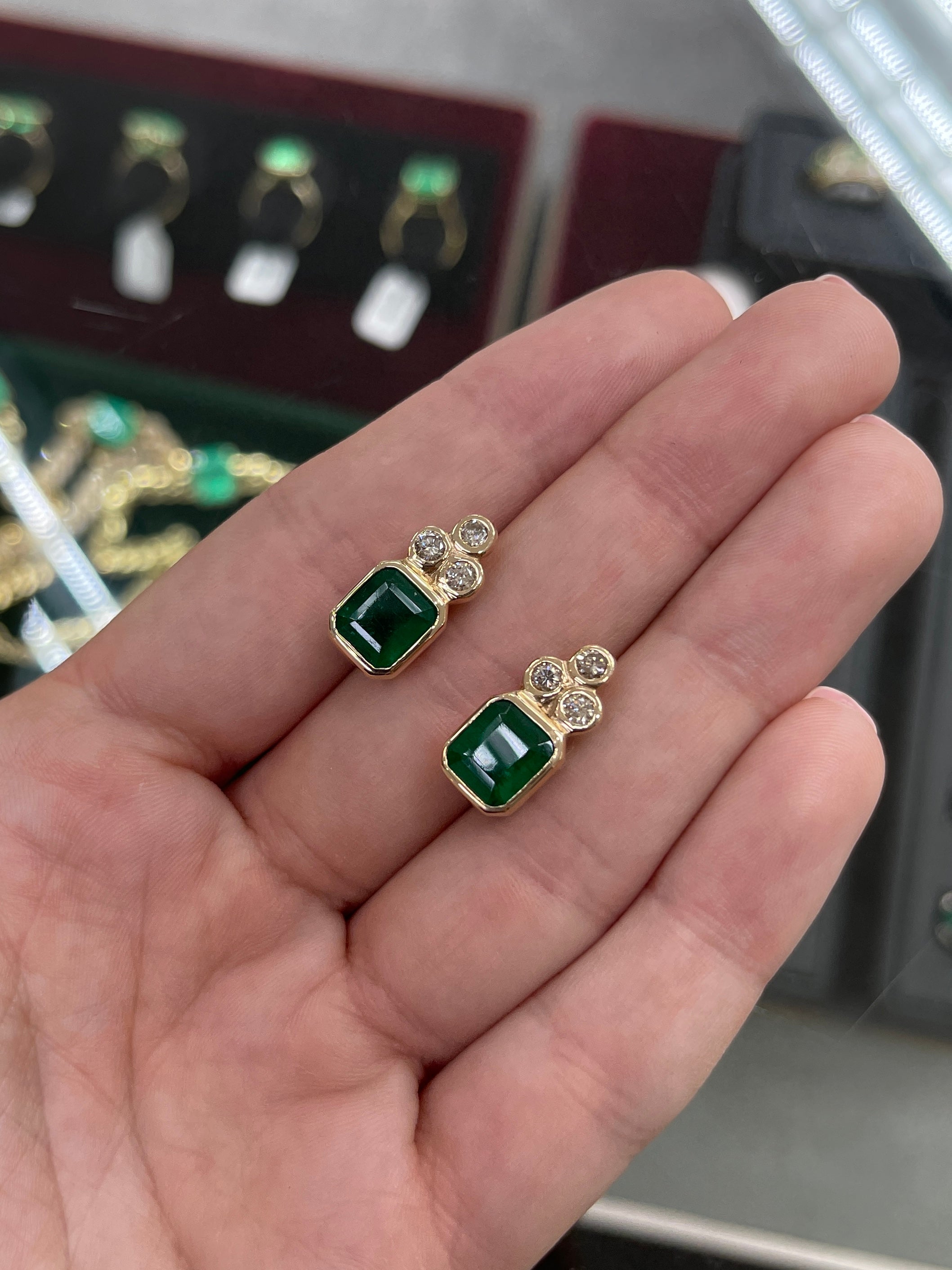 Dark green emerald-cut emerald earrings with diamond accents in 14K bezel setting by JR Colombian Emeralds.