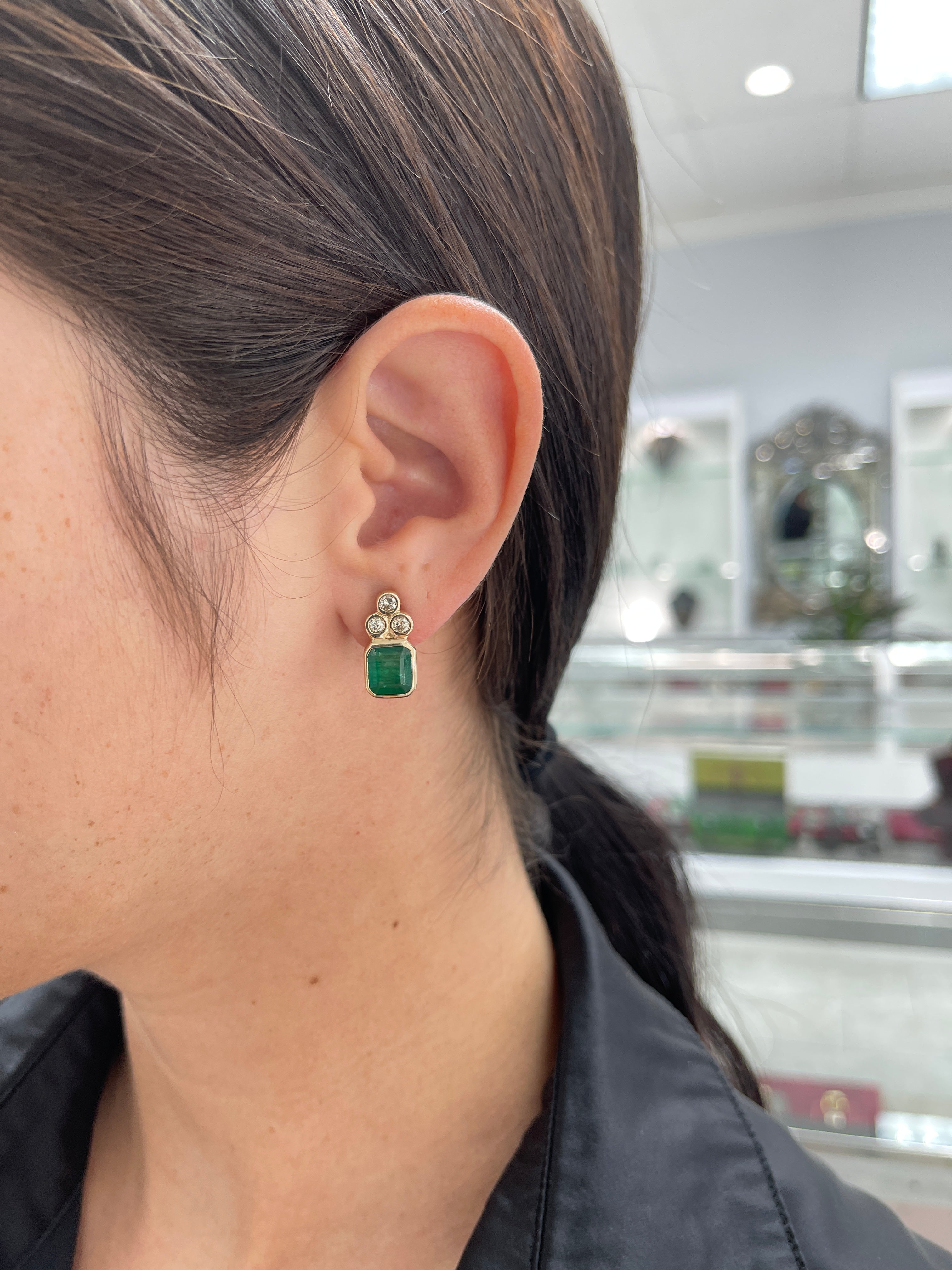 Dark green emerald cut earrings with diamond accents in 14K gold, featuring natural emeralds from JR Colombian Emeralds.