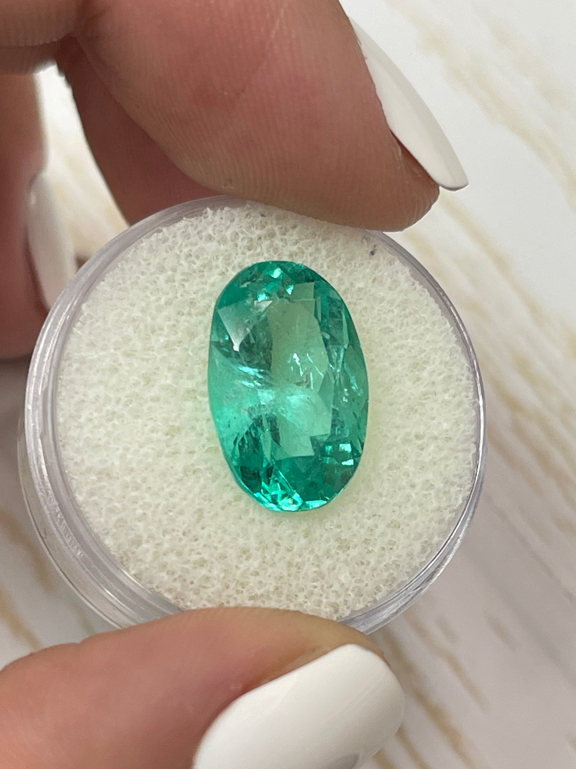 7.55 carat elongated oval Colombian emerald by JR Colombian Emeralds showing a bluish green hue and natural clarity.