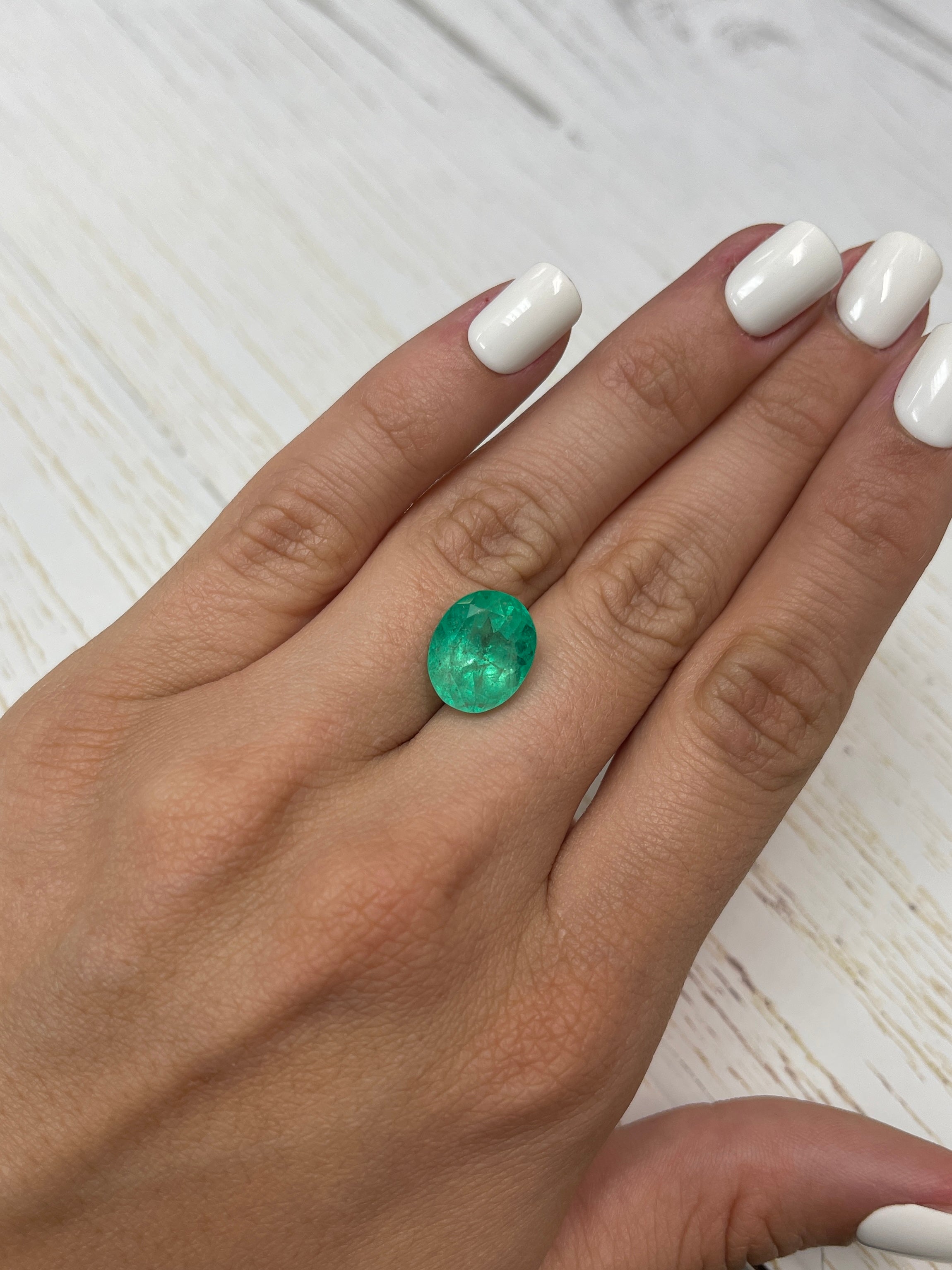 7.80 carat medium yellowish-green natural Colombian emerald in oval cut, showcasing vibrant color and clarity.