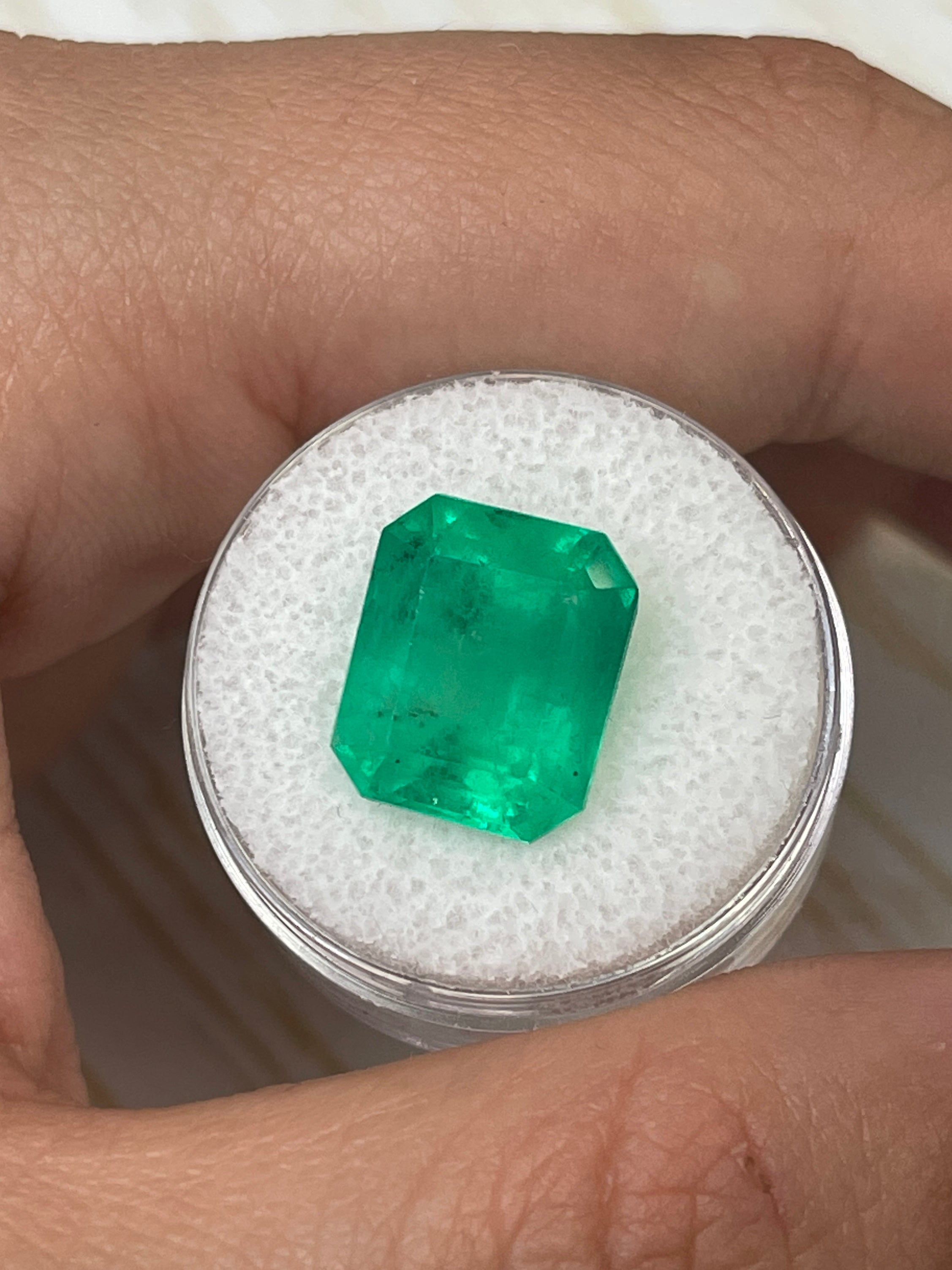 Loose 9.28 carat yellowish green Colombian emerald cut gemstone with emerald shape, showcasing clarity and vibrant color.