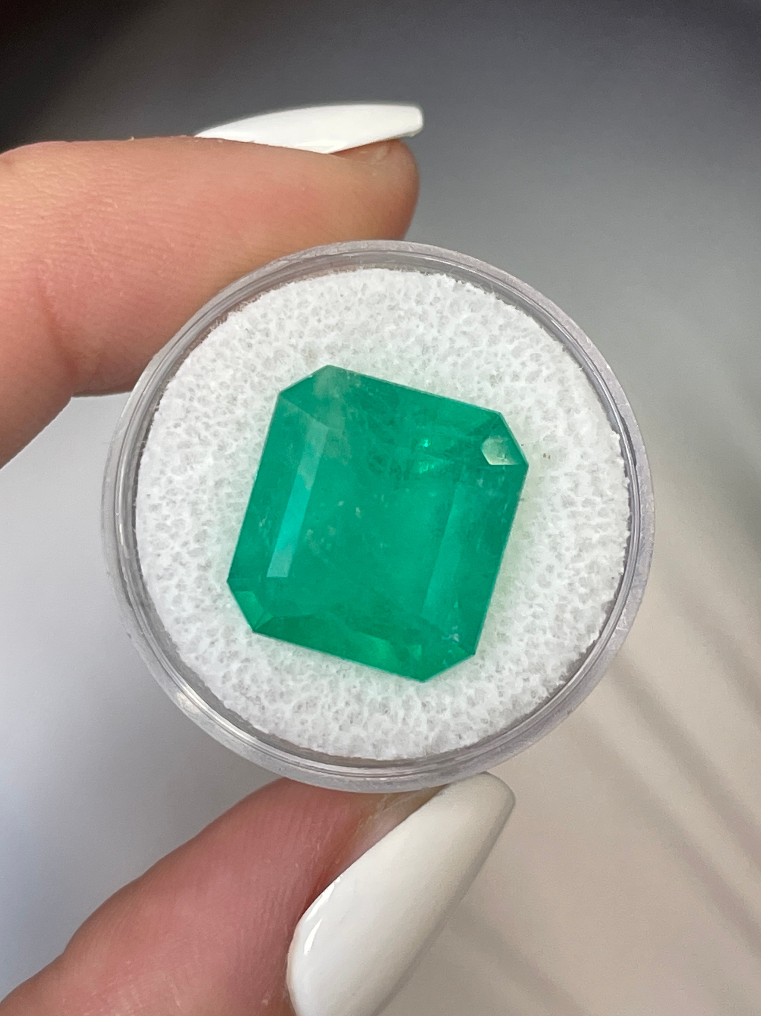 Large 12.09 Carat 15x14mm loose Colombian emerald in Asscher cut, showcasing vibrant green color and clarity.