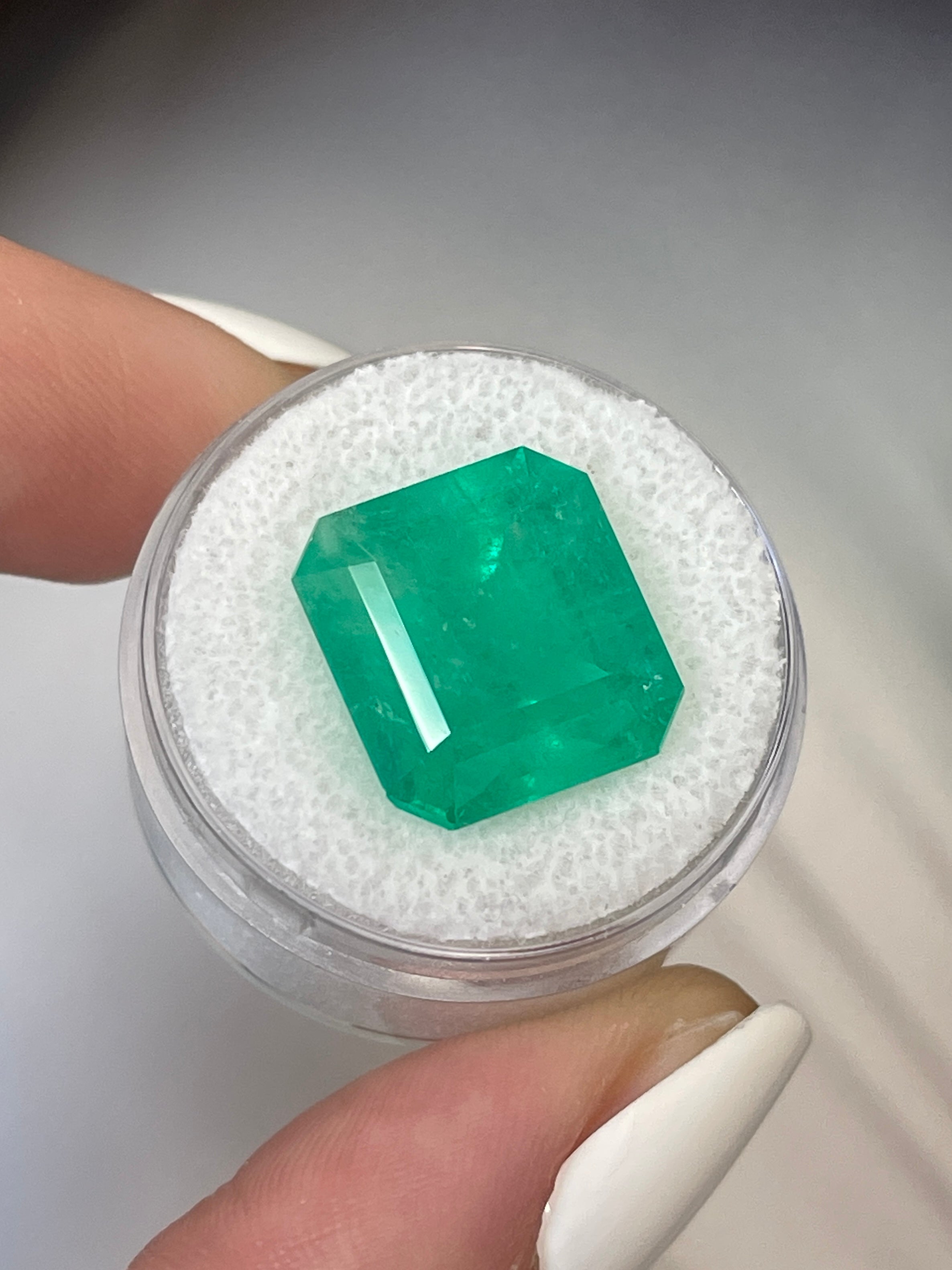 Large 12.09 carat 15x14mm loose Colombian emerald in an Asscher cut, showcasing vibrant green color and clarity.