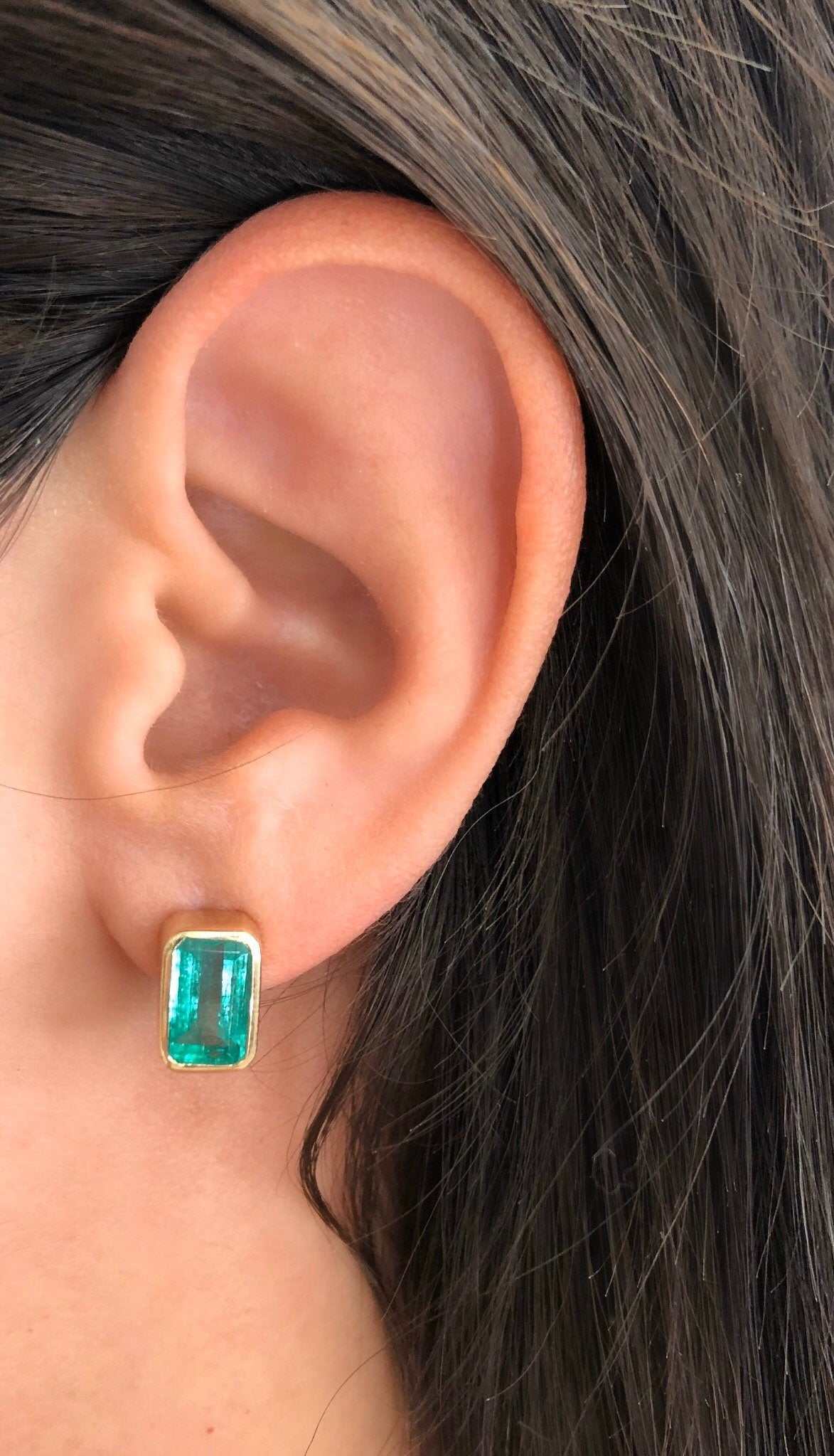 High-quality emerald cut Colombian emerald stud earrings bezel set in 14K gold, featuring 4.86tcw of vibrant green gemstones.