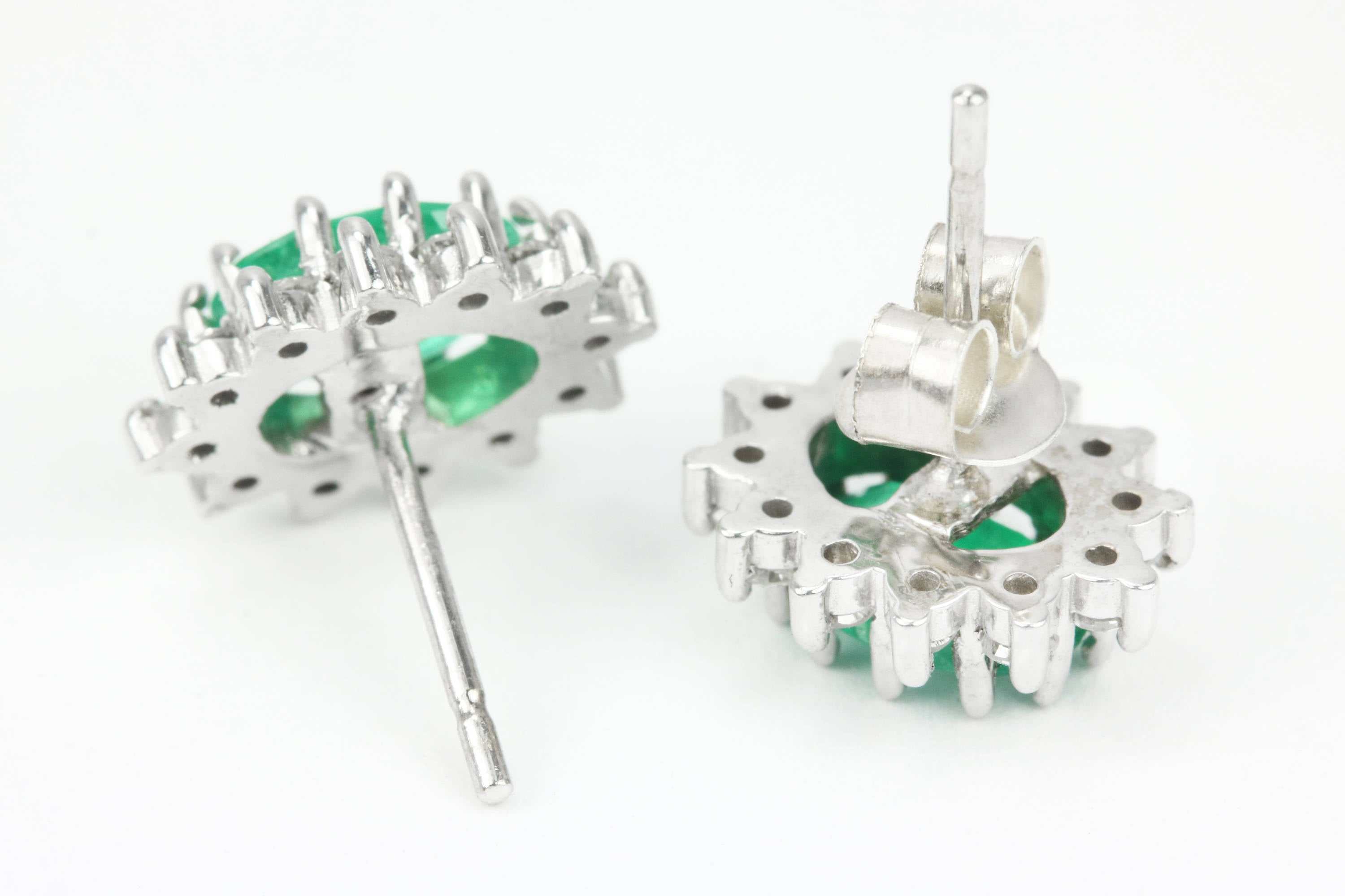 14K gold earrings with oval cut emerald and round diamond cluster halo, featuring intricate jewelry craftsmanship.